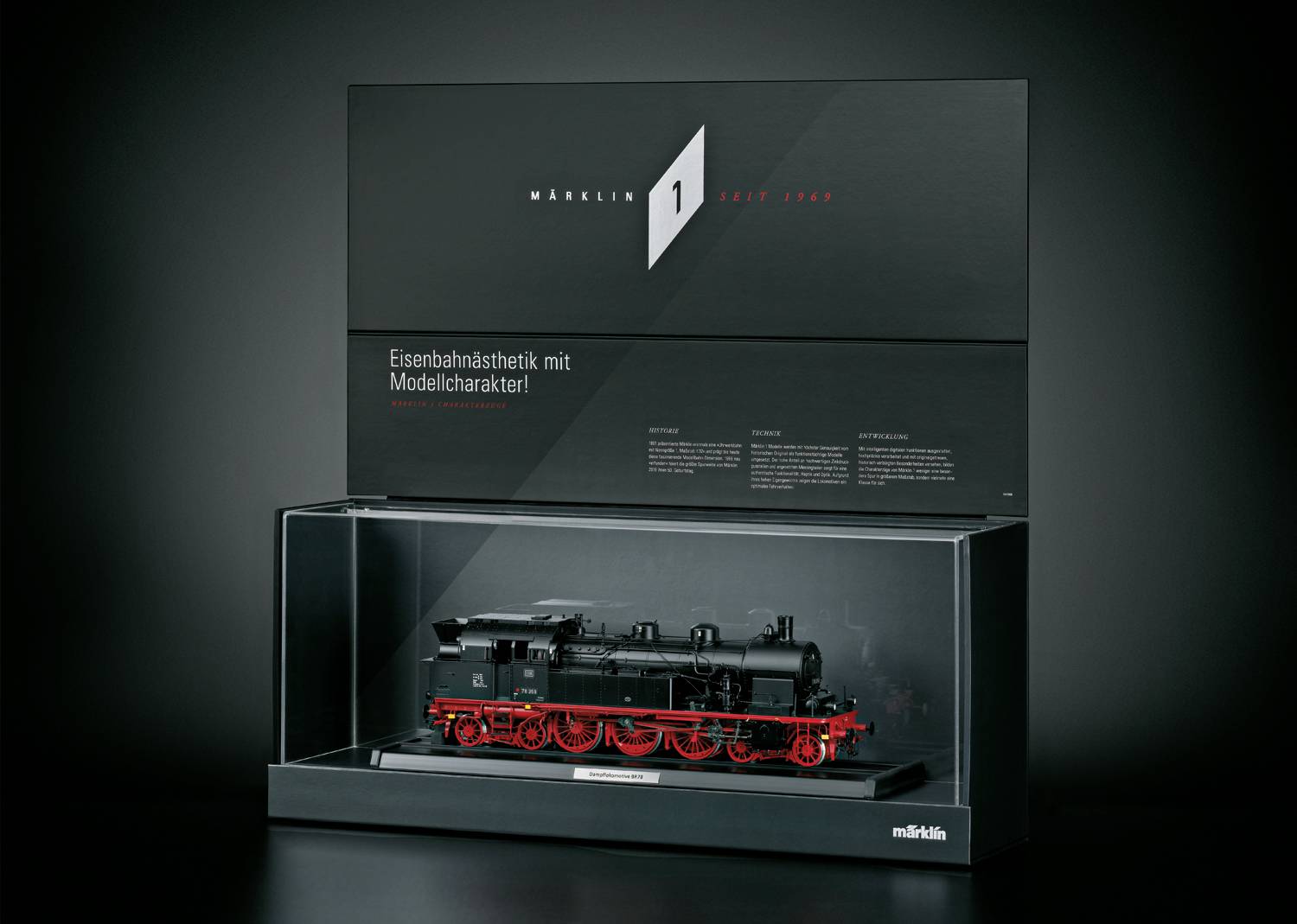 Een zwarte modeltrein met rode wielen in een glazen vitrine, gepresenteerd door Märklin. Tekst: 'Spoorwegesthetiek met modelkarakter'.