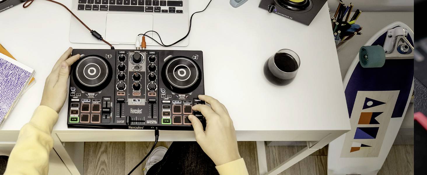 Een persoon mixt muziek op een DJ-controller aan een bureau. Naast de controller staat een laptop. Rechts staat een glas met een drankje.