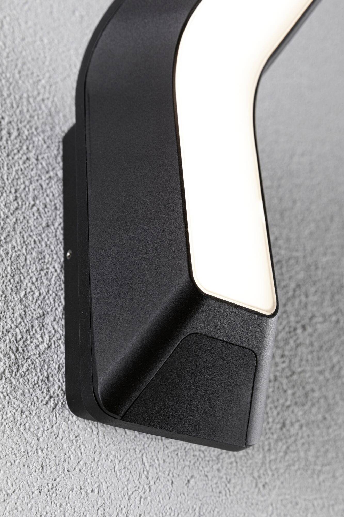 Zwarte, moderne wandlamp met een gebogen ontwerp, bevestigd aan een grijze, gestructureerde oppervlakte.