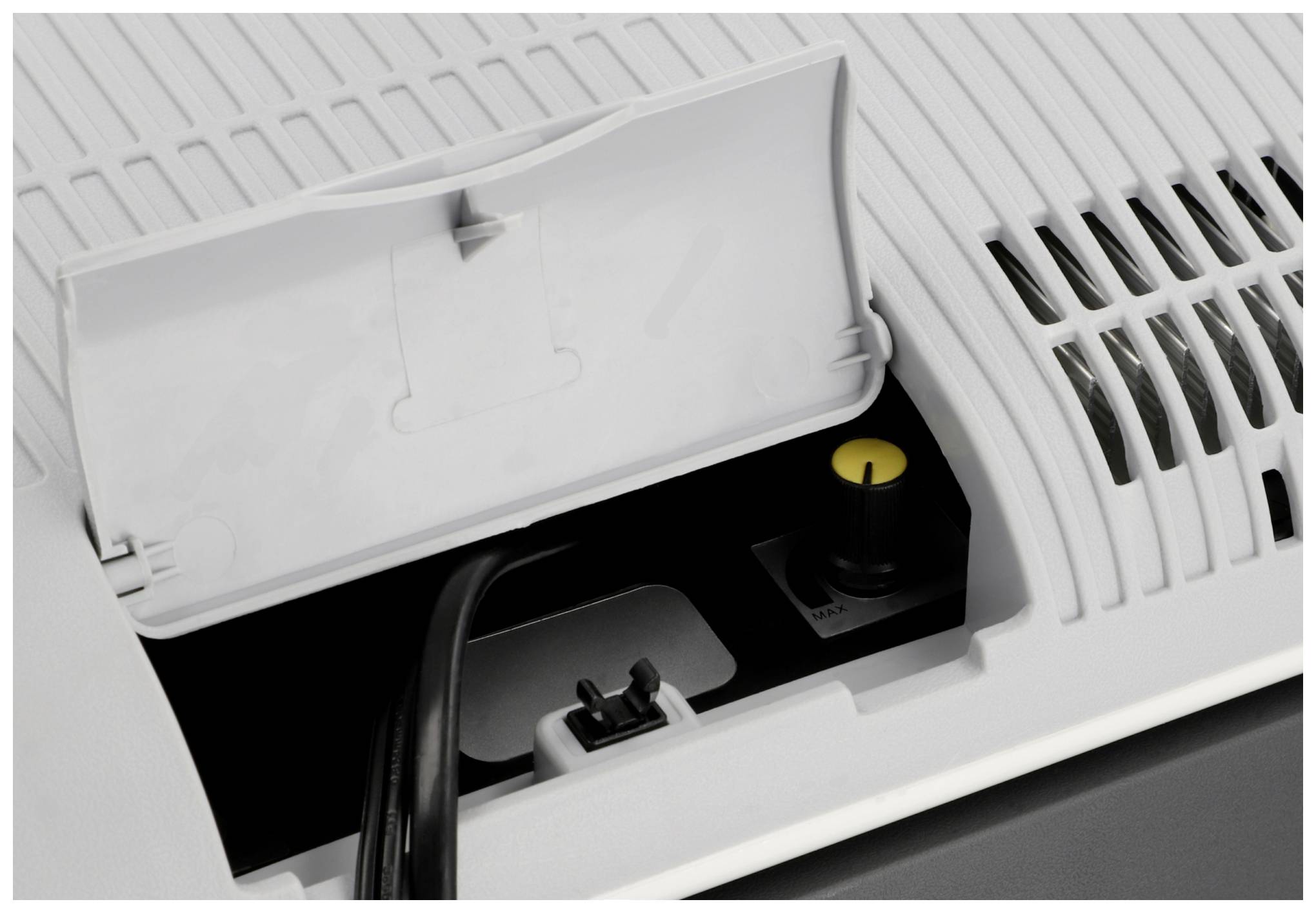 Een open vak van een apparaat toont een kabelaansluiting en een gele knop. Enkele ventilatiesleuven zijn zichtbaar.