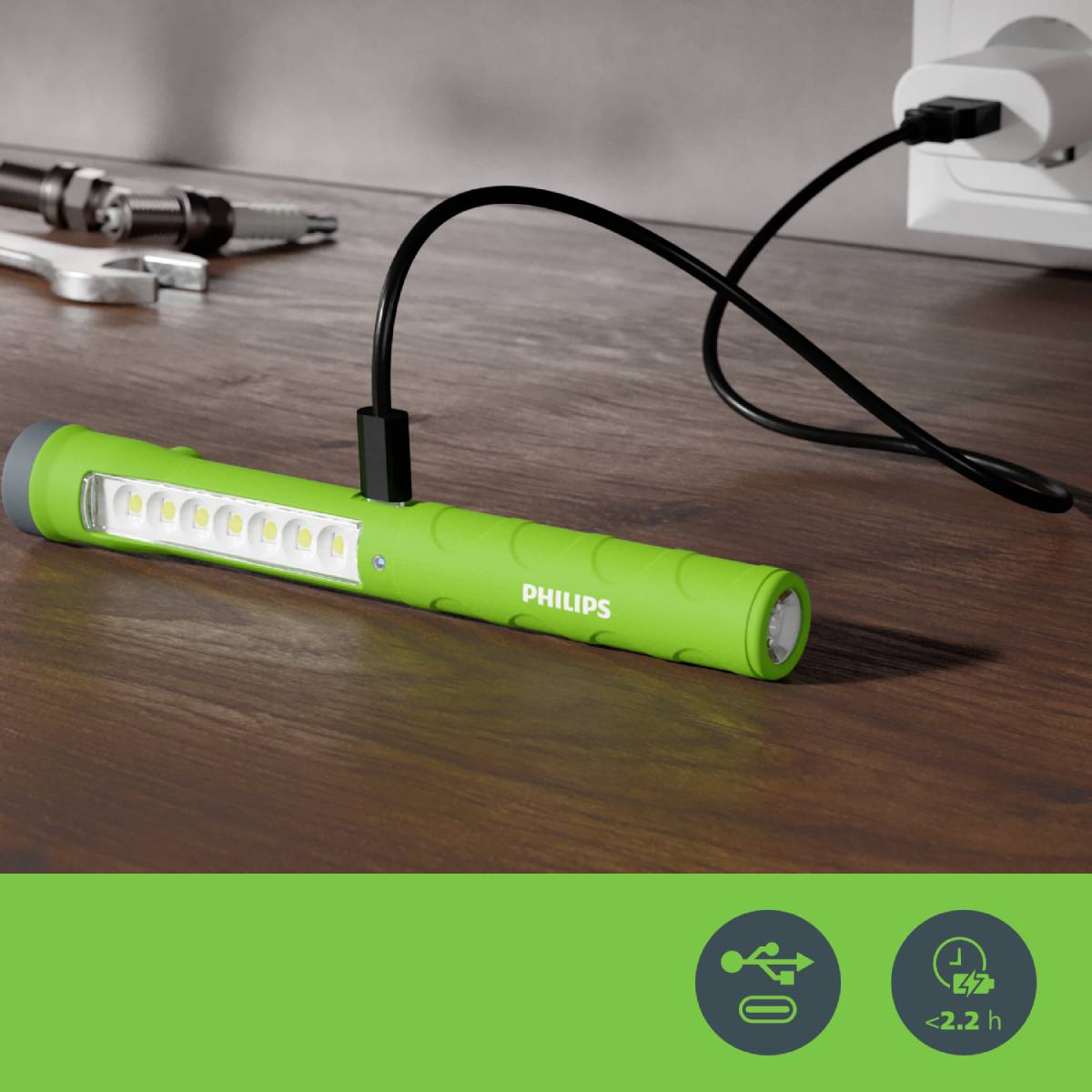 Groene, oplaadbare LED-stang van Philips ligt op een tafel en is aangesloten op een stopcontact.