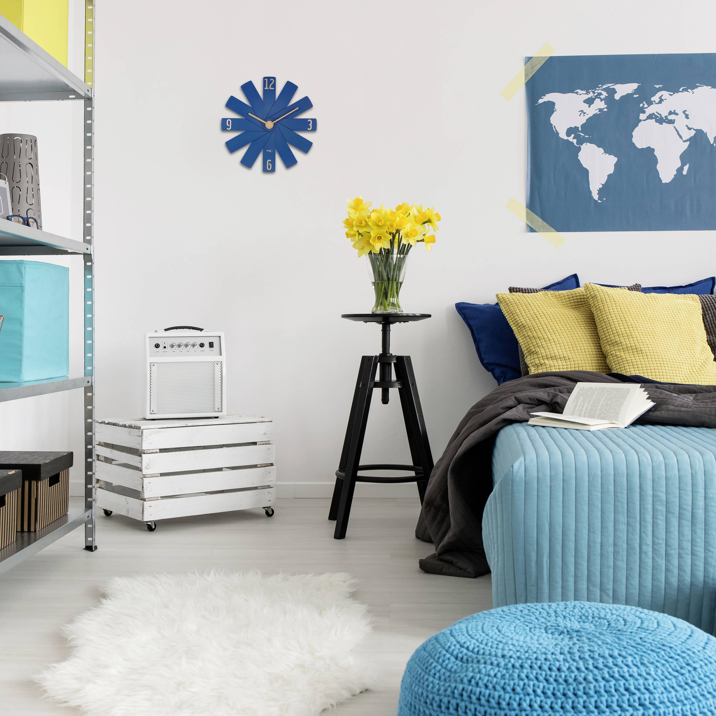 Woonkamer met moderne stijl: Blauwe, bolvormige kruk, gele bloemen op een statief, wereldkaart aan de muur, blauwe bank.