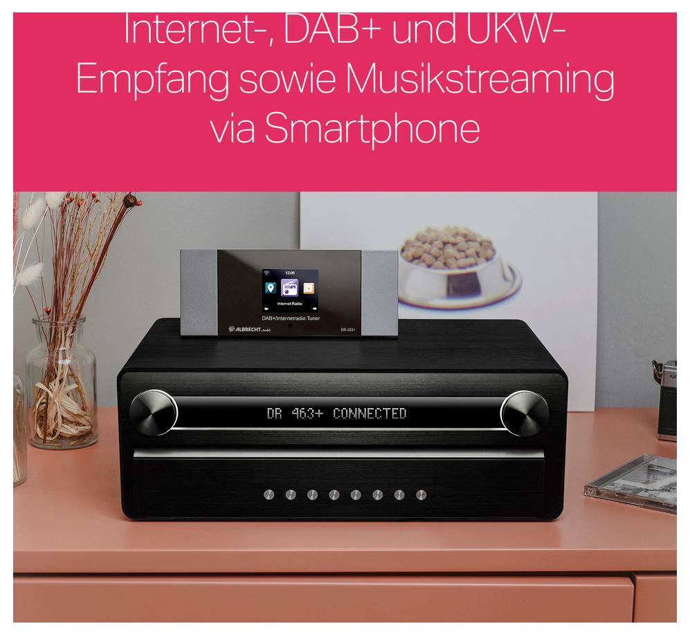 Een zwart digitaal radio staat op een tafel. Bovenaan toont een display 'DR 463+ CONNECTED'. Op de achtergrond een bord met gebak.