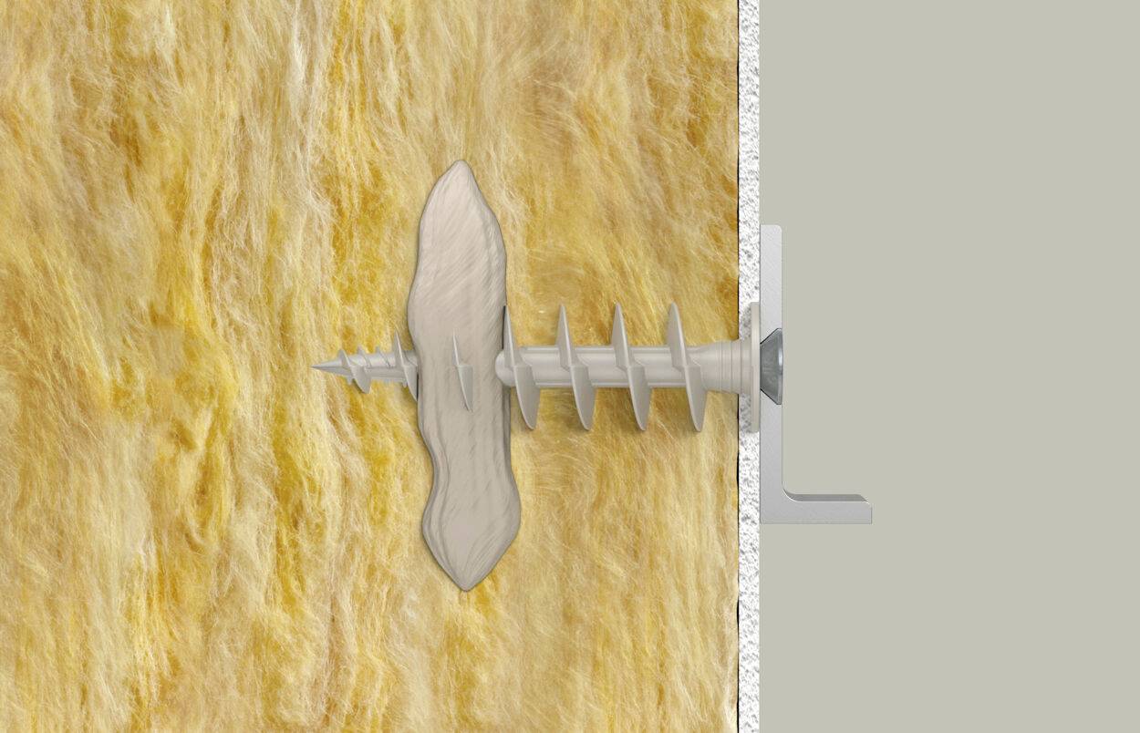 Een gipspluggen wordt in een gele isolatieplaat aan de muur geschroefd.