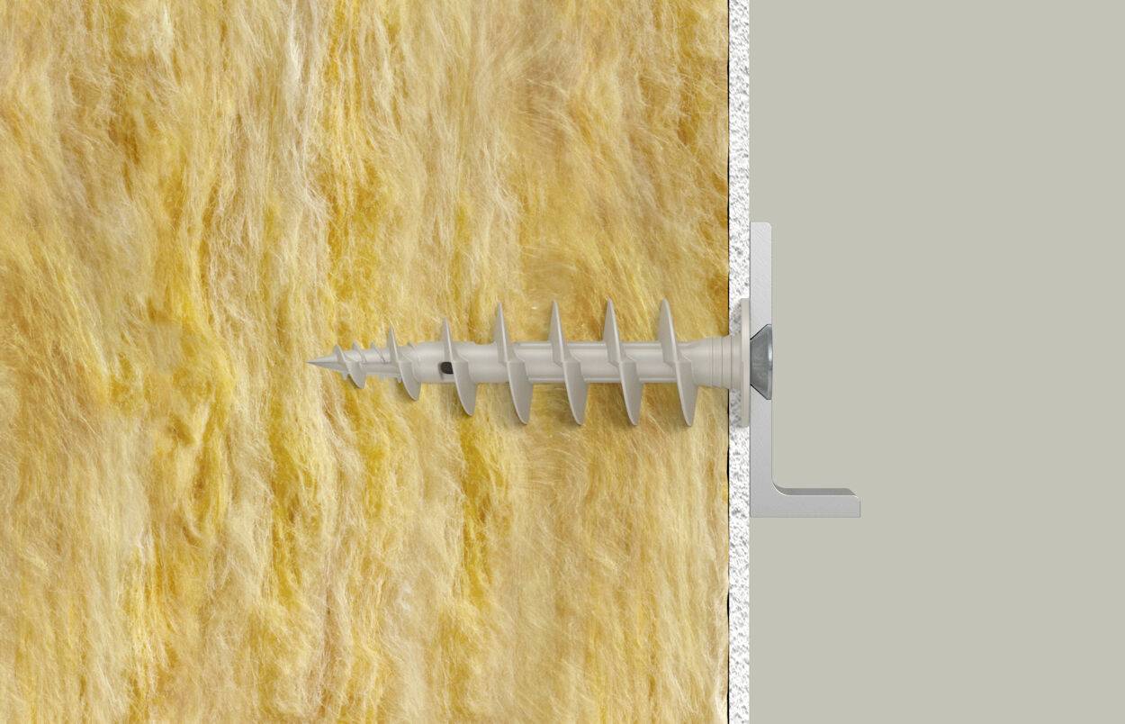 Een schroef wordt door een gele isolatielaag in een grijze muur gedraaid. Een metalen stuk houdt de schroef stabiel.