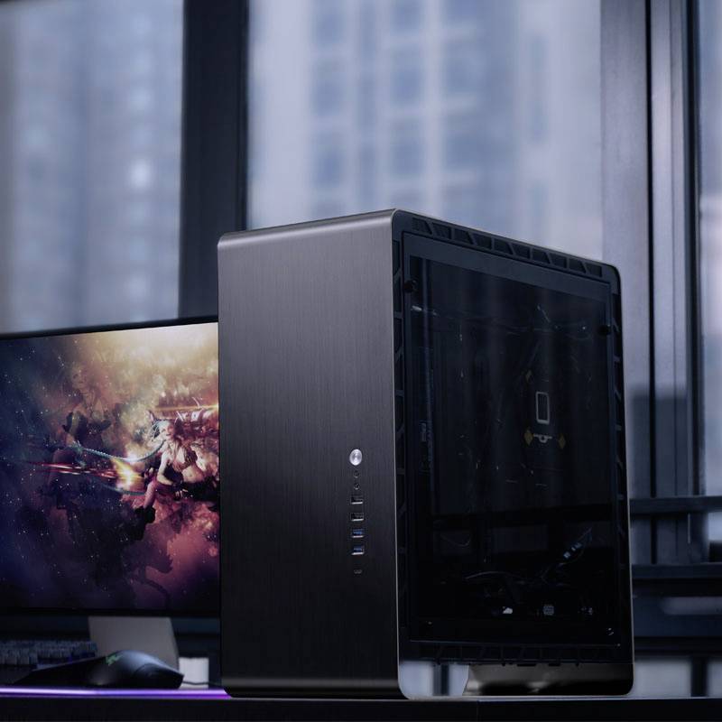 Een zwarte computer-toren staat op een tafel voor een raam, naast een monitor met een fantasy-computerspel.