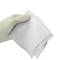 Gehandschoende hand met een gevouwen witte doek of gaascompres tegen een effen achtergrond.
