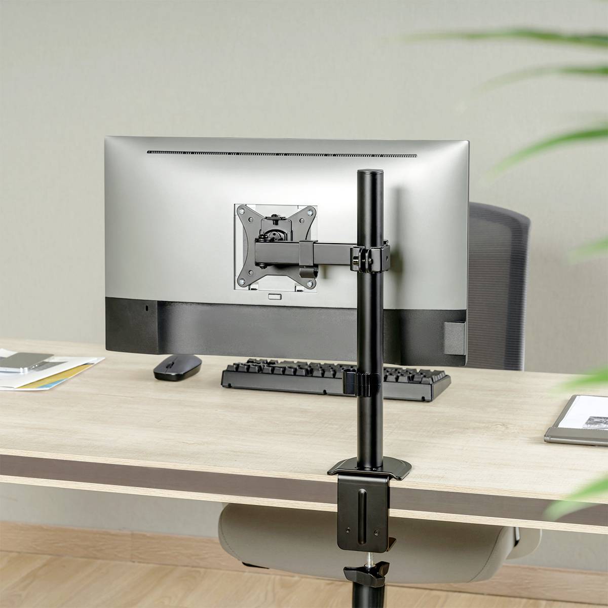 Een computermonitor is aan de achterkant bevestigd aan een hoogteverstelbare steun. Het bureau is van licht hout.
