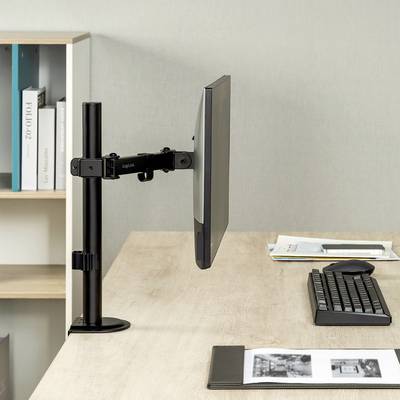 Een kantoorwerkplek met een monitor aan een verstelbare arm, computermuis, toetsenbord en notitieboek op een licht houten bureau. Op de achtergrond een plank met boeken.