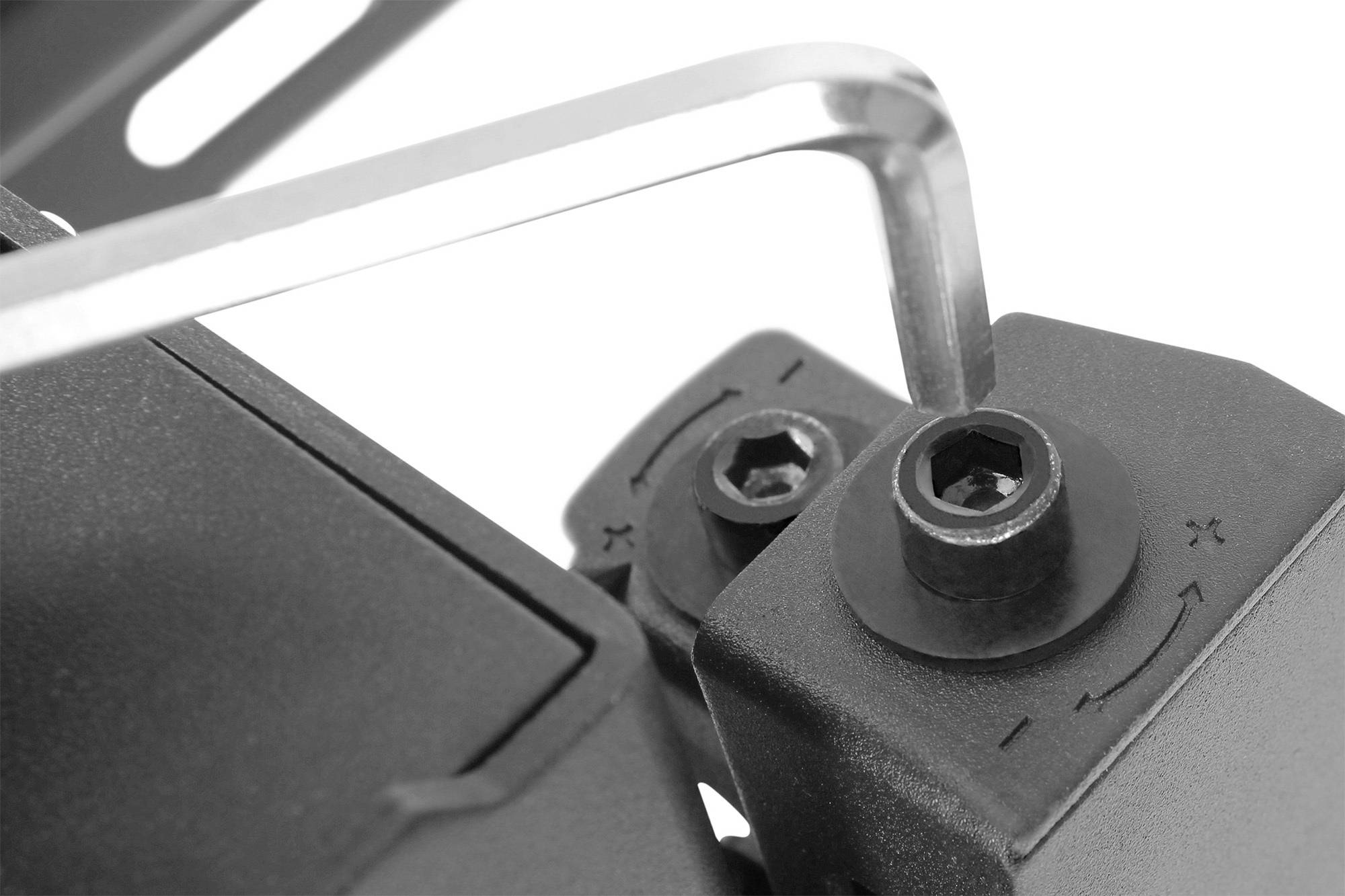 Close-upfoto van een zeskantsleutel die een schroef in een mechanisch apparaat vastdraait, tegen een witte achtergrond.