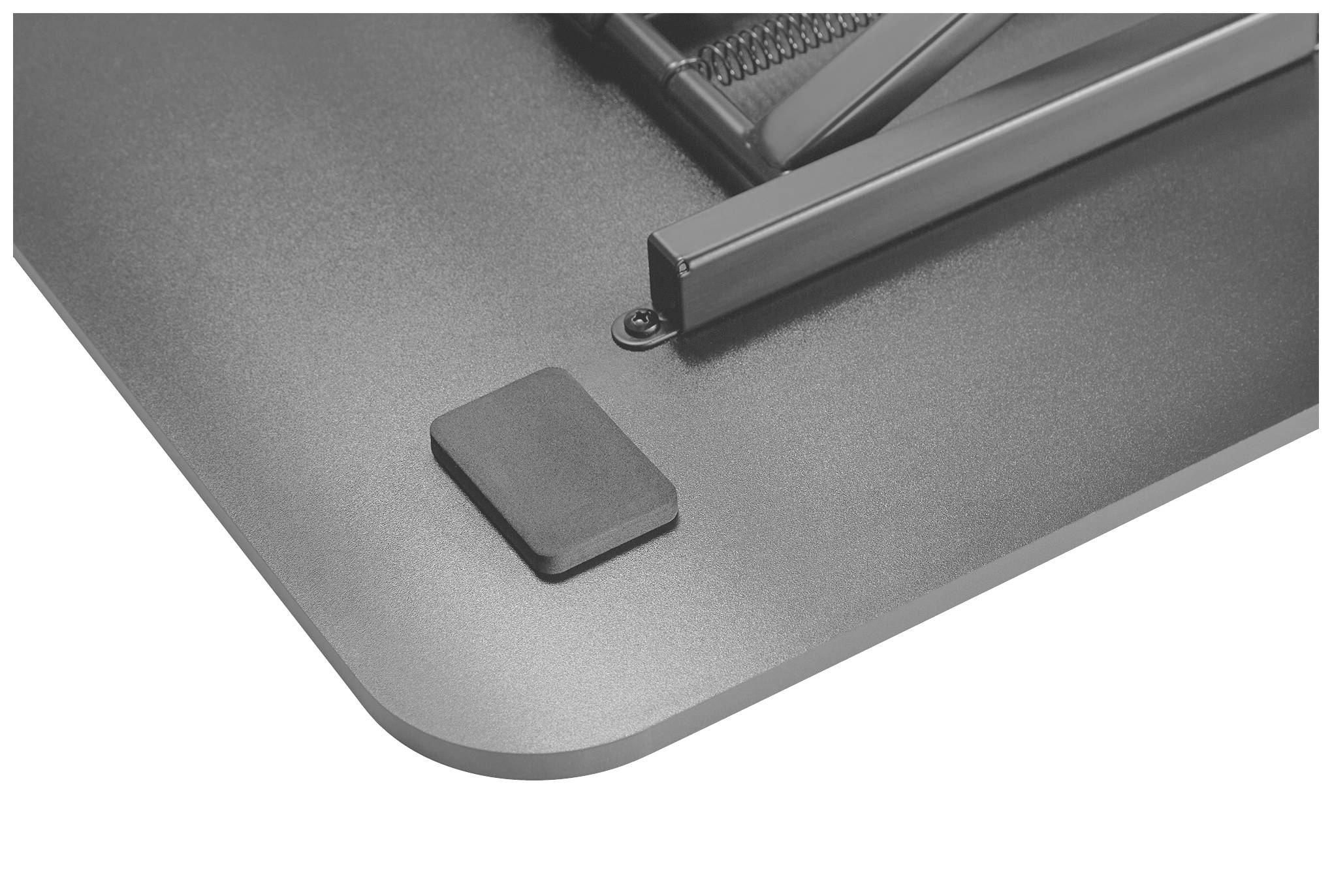 Een close-up van een donkergrijs metalen object met een vierkante rubberen oplegplaat en een daaraan bevestigde scharnierende arm.