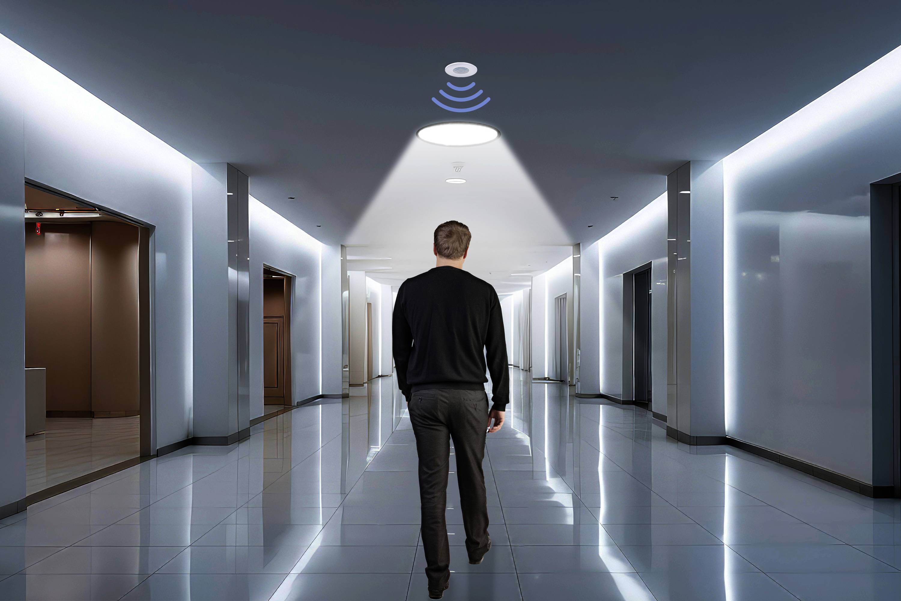 Een man loopt door een gang met sensorverlichting die zijn beweging detecteert en hem verlicht.