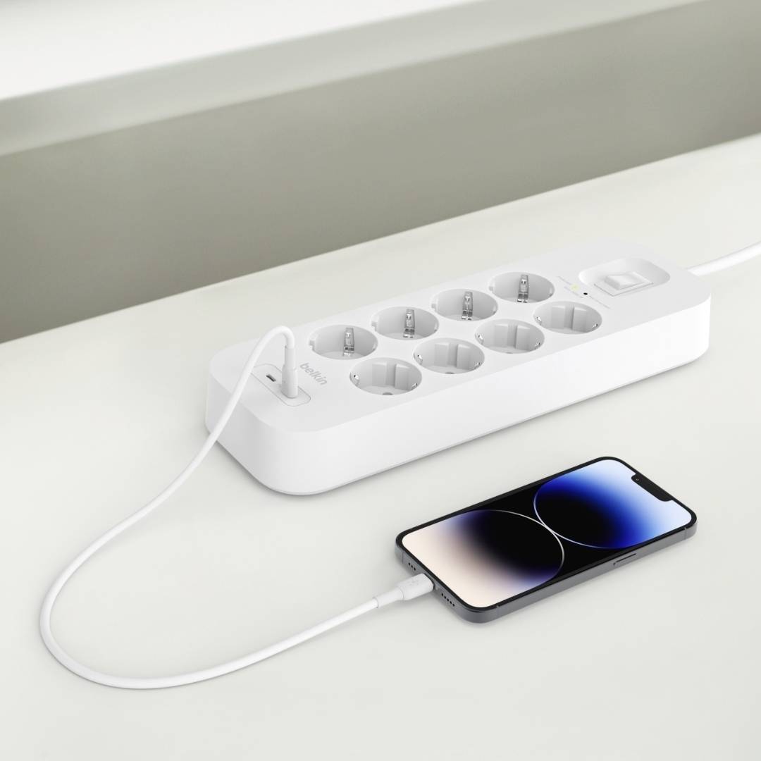 Een witte stekkerdoos met tien aansluitingen en een smartphone die via een oplaadkabel is aangesloten.