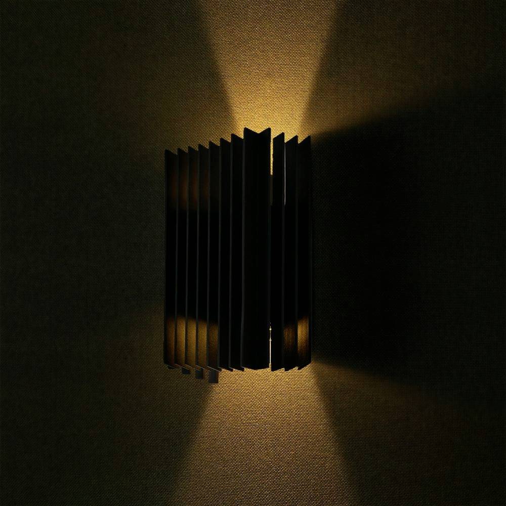 Wandlamp met verticale lamellen die warm licht naar boven en beneden uitstralen, creëert een sfeervolle ambiance aan de muur.