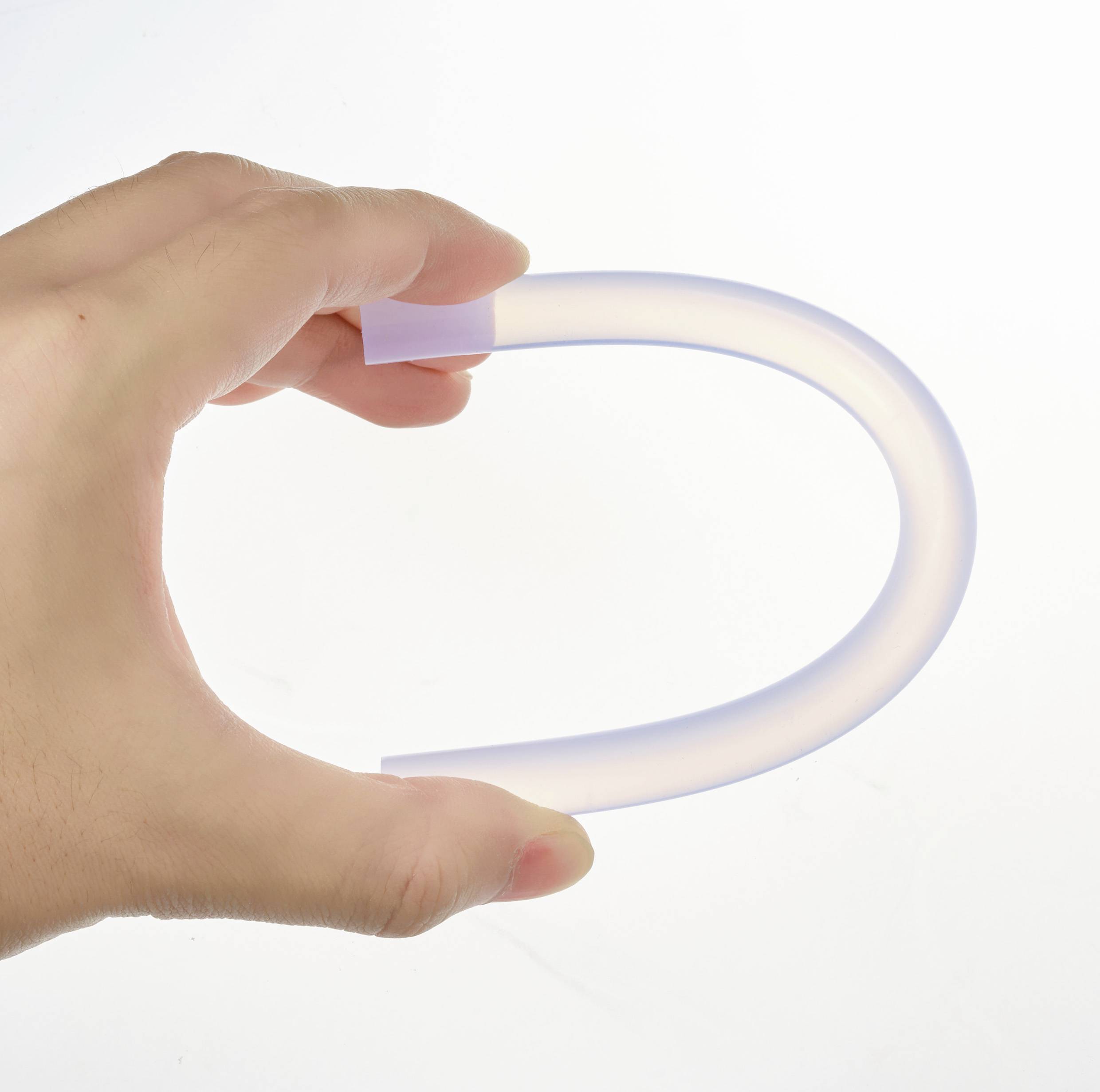 Een menselijke hand houdt een transparante, flexibele slang in een gebogen vorm voor een neutrale achtergrond.