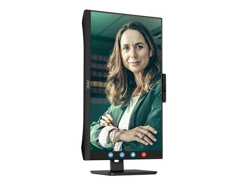 Een vrouw kijkt glimlachend in de camera, weergegeven op een staande monitor. Ze draagt een groene jas en een wit overhemd.