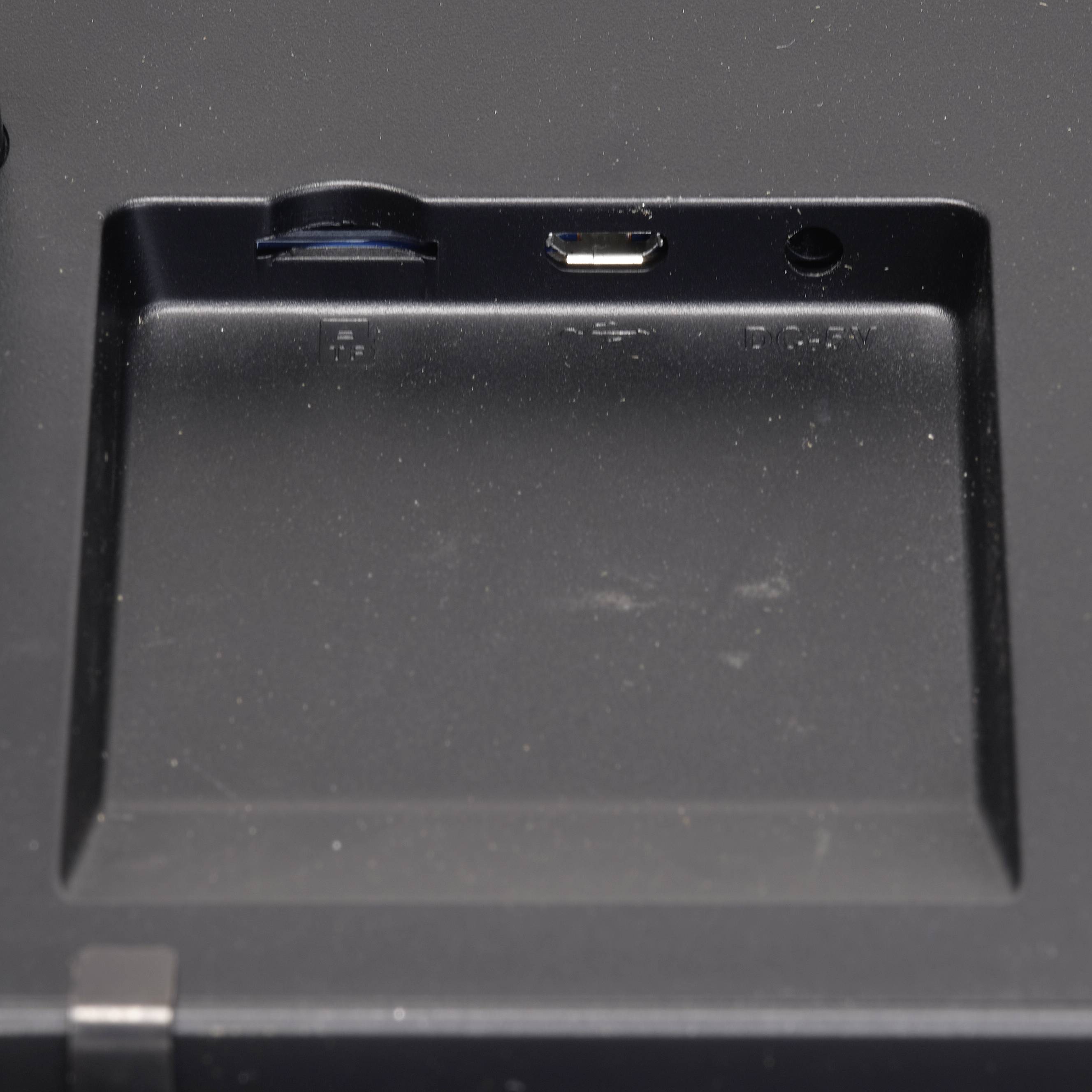 Een lege sleuf met een Micro-USB-aansluiting en audio-ingang op een zwart apparaat. Gebruikt voor externe verbindingen.