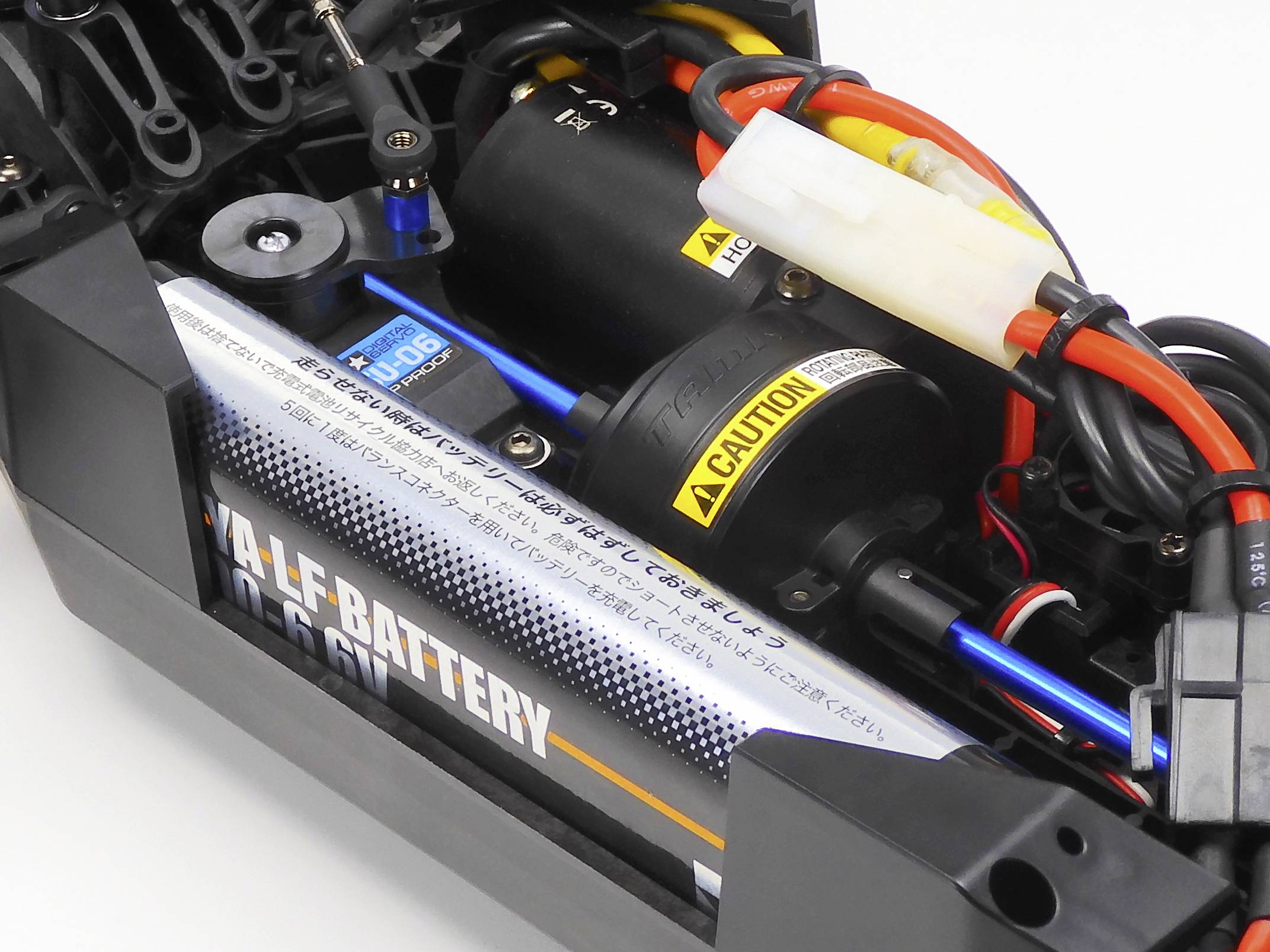Close-up van de binnenkant van een bestuurbare auto, toont motor, kabelverbindingen en batterijvak met geplaatst AA-batterijpakket.
