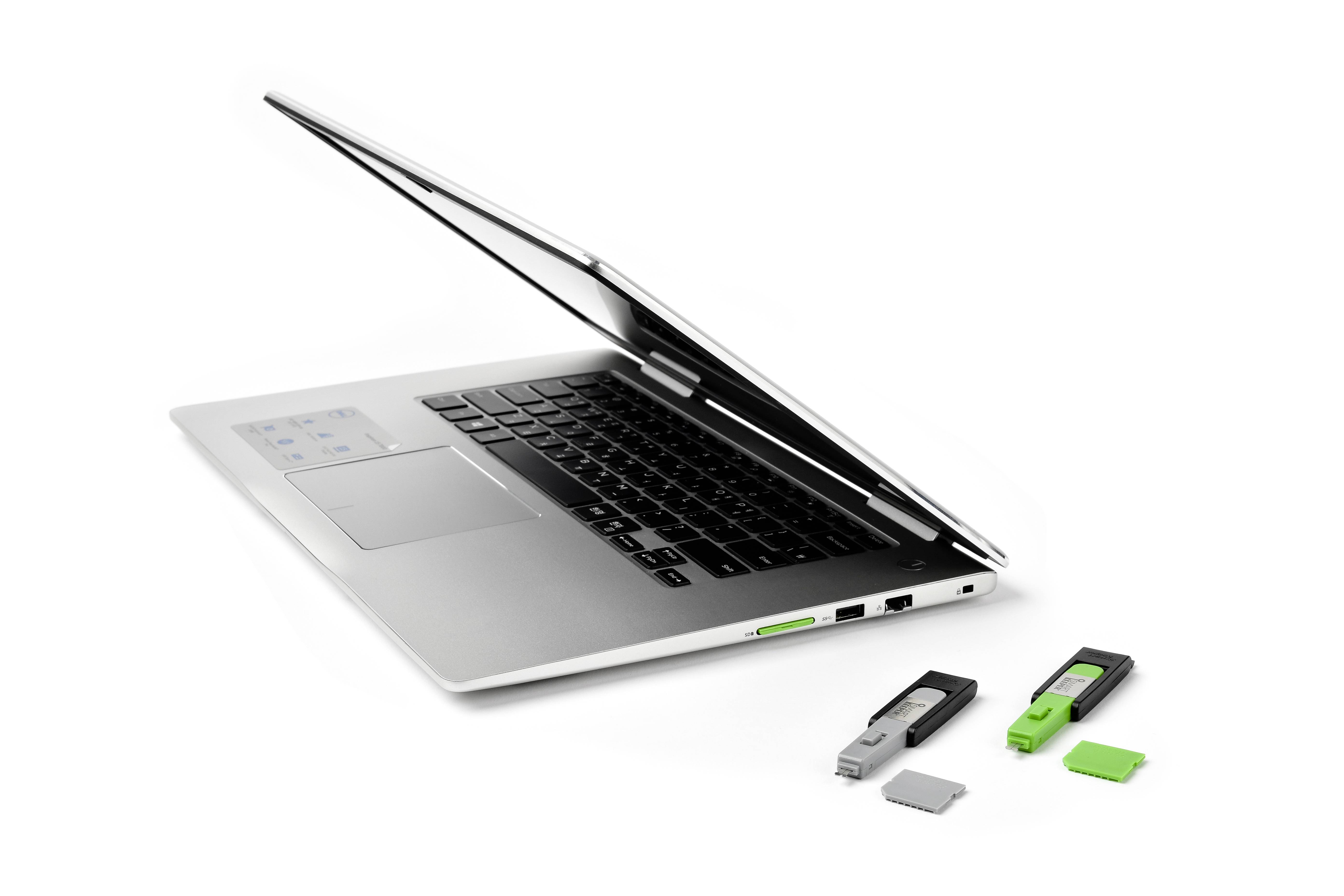 Zilveren laptop met licht opengeklapte scherm, ernaast drie USB-sticks in zwart en groen en een geheugenkaart.