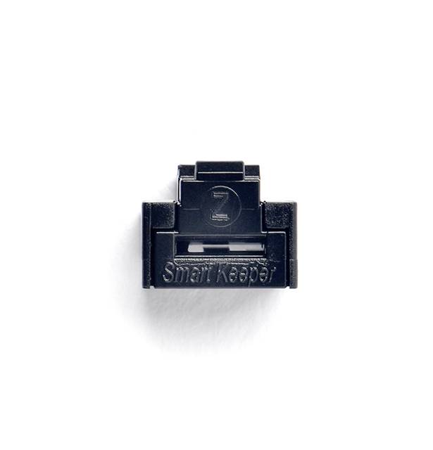 Een zwarte, vierkante USB-poortafsluiting met het opschrift 'Smart Keeper' op een witte ondergrond.