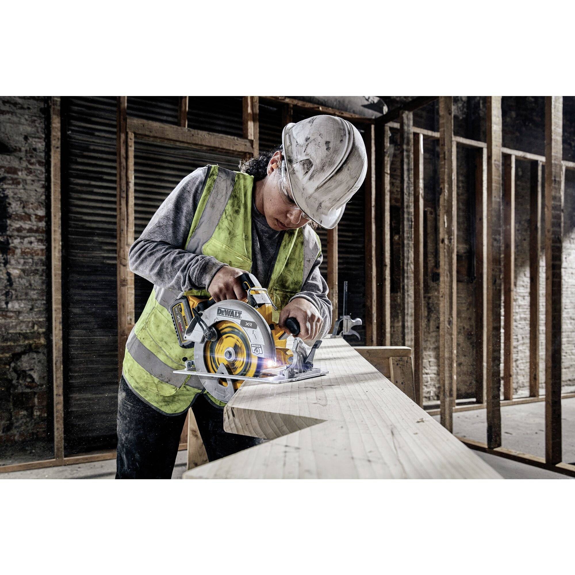 Een persoon met een veiligheidshelm en veiligheidsvest werkt met een elektrische cirkelzaag op een bouwplaats.