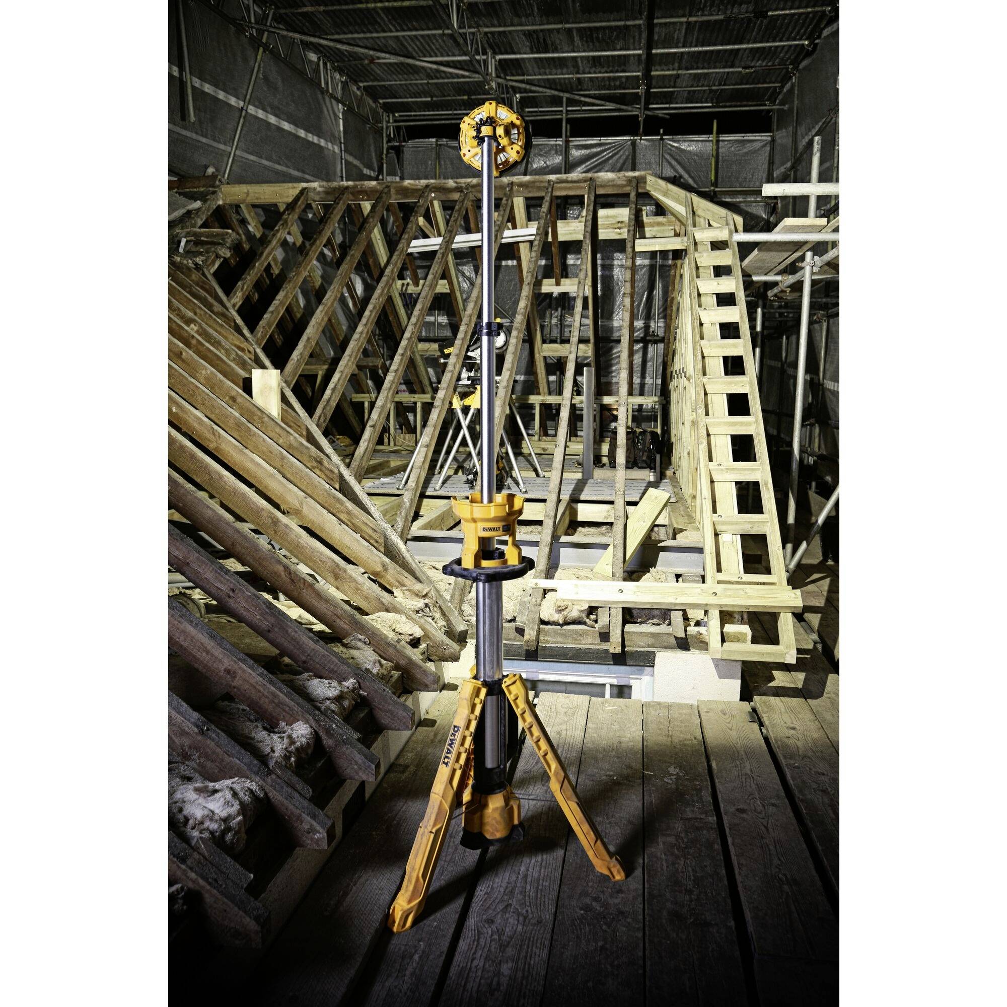 Een meetinstrument staat op een bouwplaats met houten constructies op de achtergrond. Het wordt gebruikt voor gebouwopmetingen.