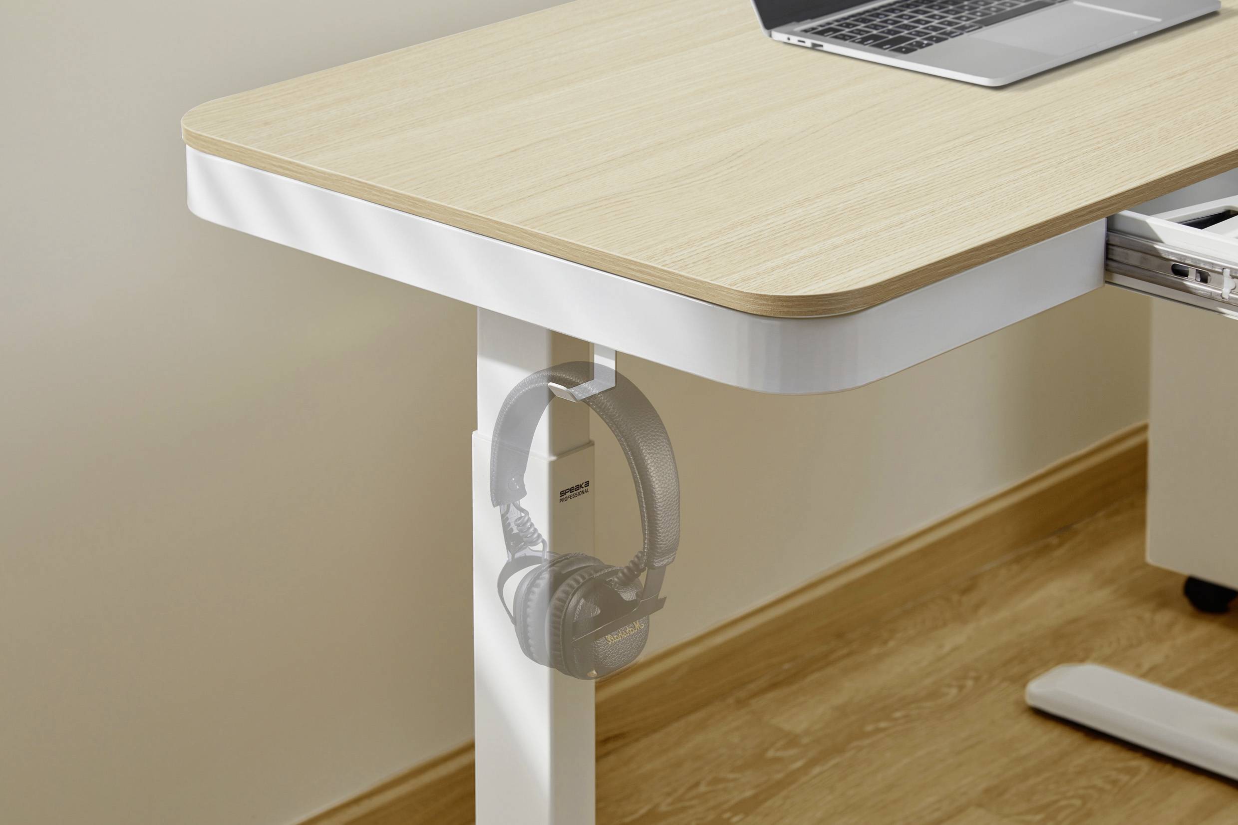 Houten tafel met laptop, daaronder koptelefoon aan een haak bevestigd aan de tafelrand.