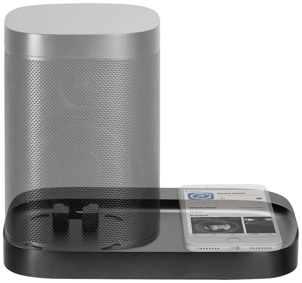 Een ovale, zilveren smart-speaker met een cilindrische vorm staat op een oplaadstation naast een liggend smartphone.