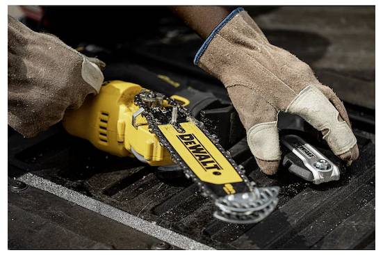 Een persoon met handschoenen bedient een DeWalt kettingzaag op een houten oppervlak, waarbij houtspaanders zichtbaar zijn, wat wijst op actief zaagwerk.