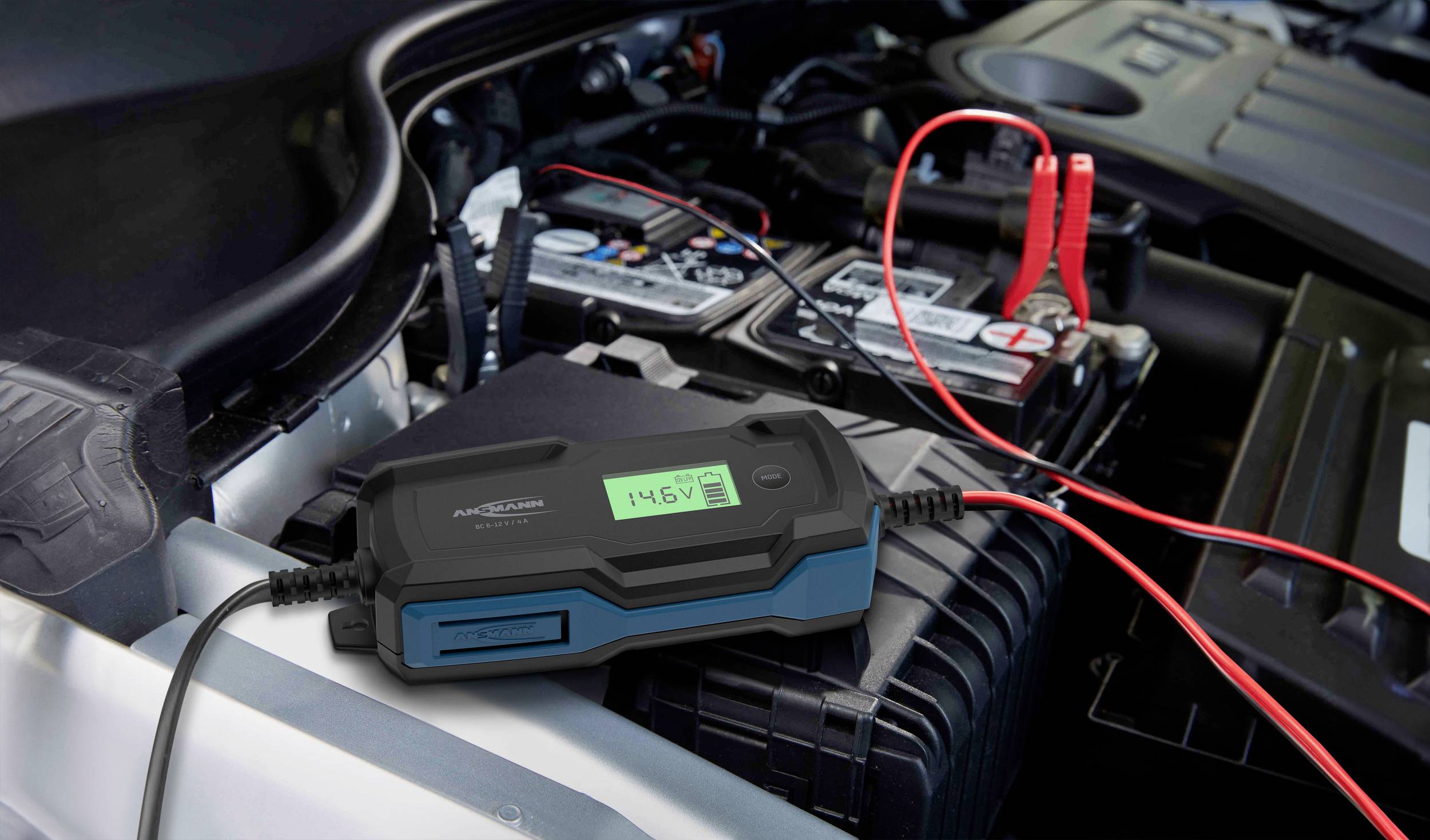 Een batterijlader is aangesloten op de autobatterij van een voertuig. Het apparaat geeft een spanning van 14,6V aan.