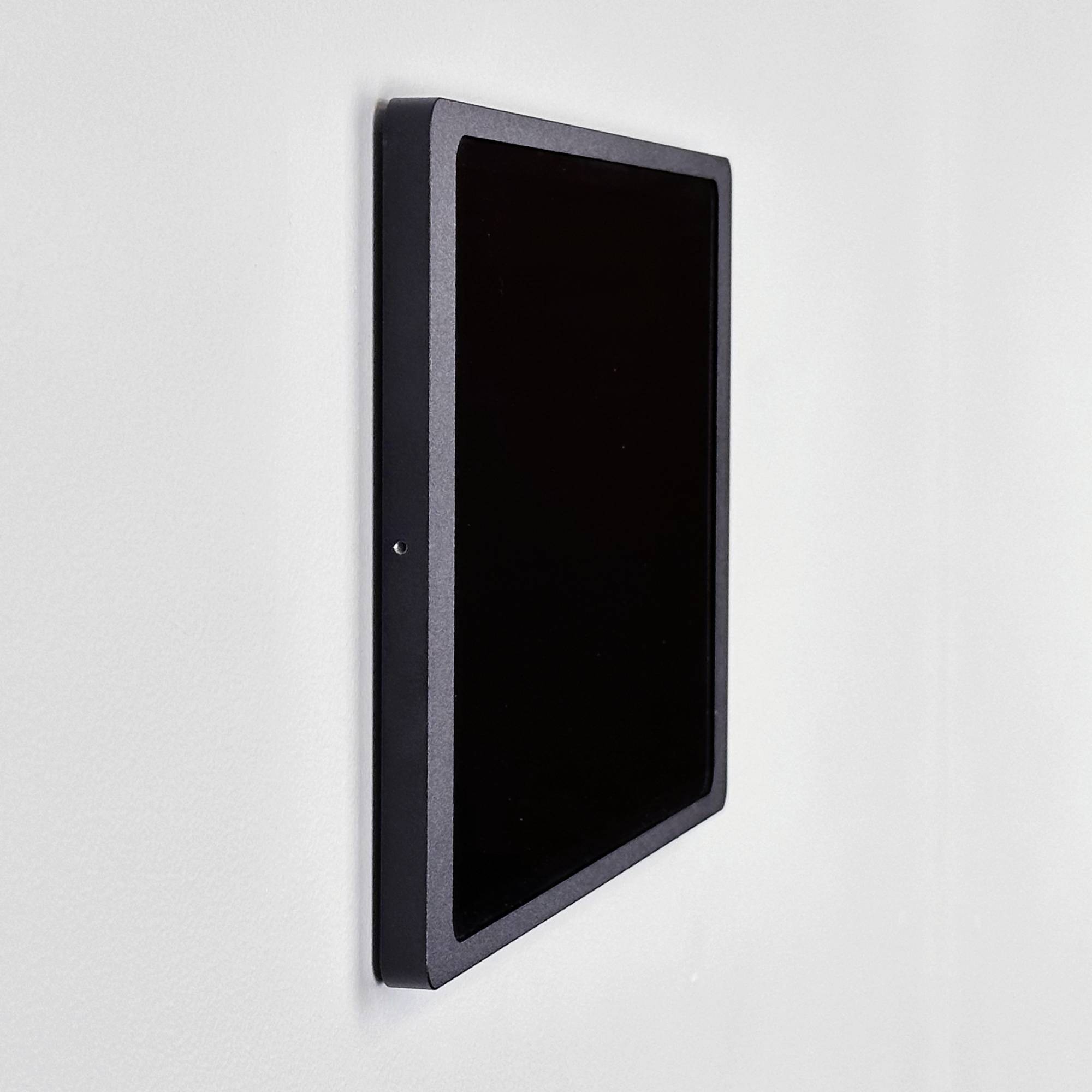 Een zwarte, wandgemonteerde monitor vertoont geen weergave. Het apparaat is gefotografeerd vanuit een zijdelingse perspectiefhoek.