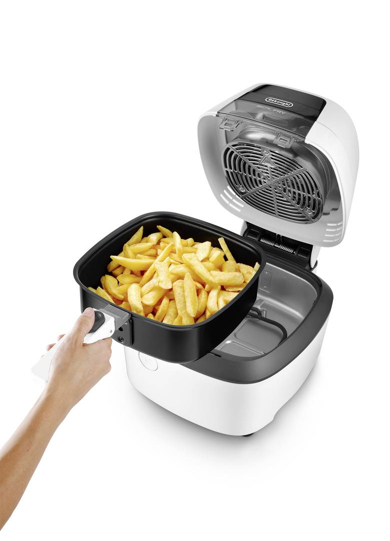 Een persoon houdt een mandje met friet vast en plaatst het in een geopende airfryer.