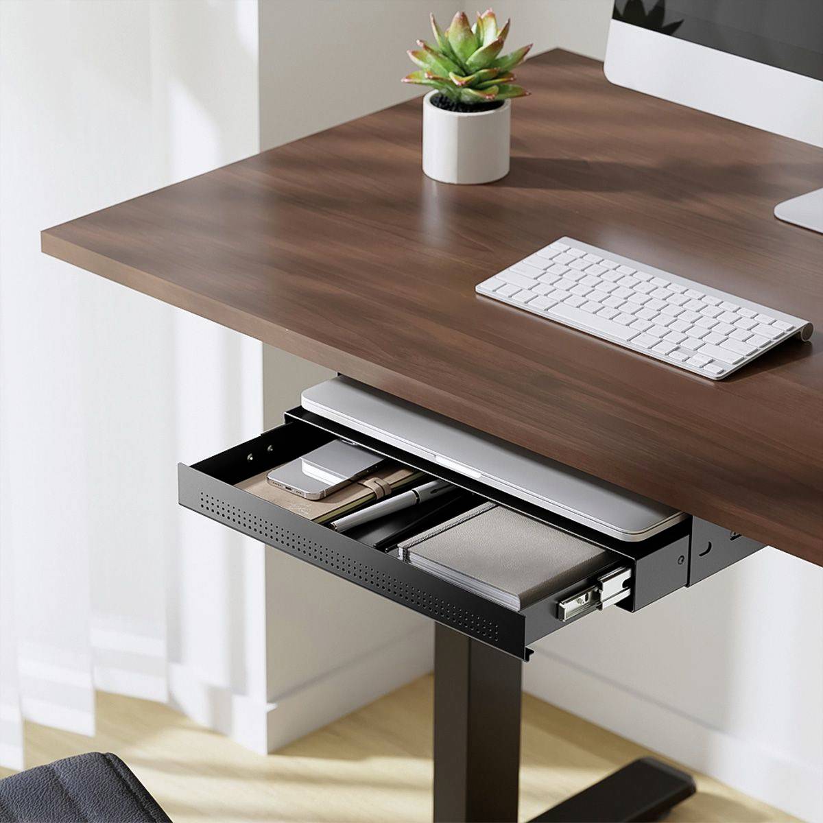 Bureau met laptop, toetsenbord en kleine bloempot. Een lade toont documenten en notitieboeken. Lichte, heldere ruimtesfeer.