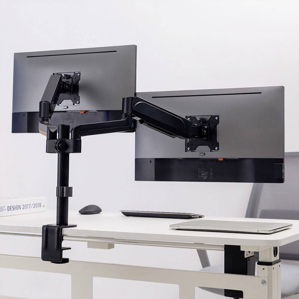 Twee monitoren zijn gemonteerd op een dubbele monitorsteun aan een bureau, wat flexibel werken en ergonomische positionering mogelijk maakt.