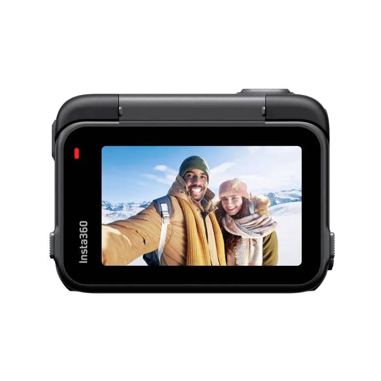 Een lachend stel in winterkleding maakt een selfie voor een besneeuwde bergachtergrond, weergegeven op het scherm van een camera.