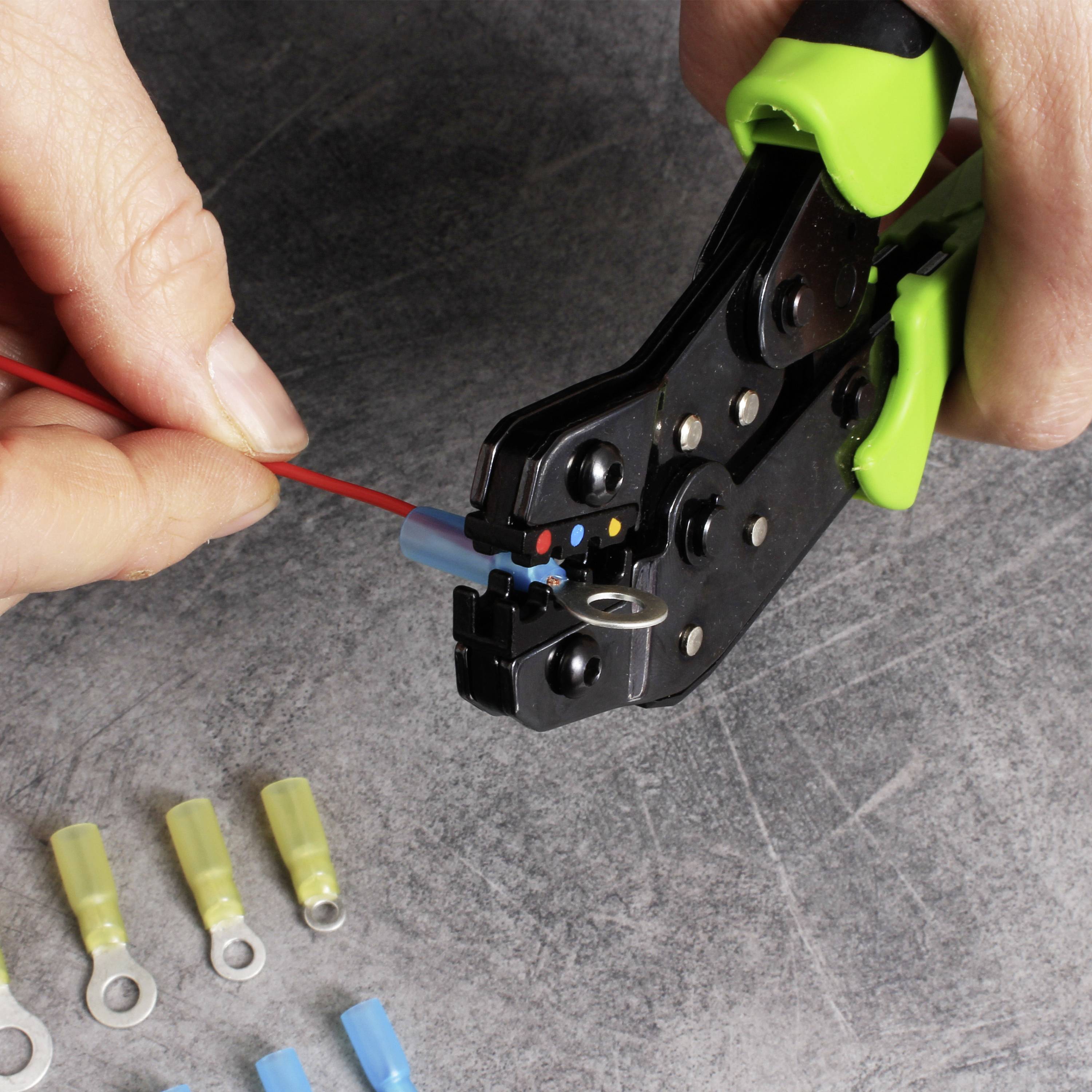 Een persoon gebruikt een krimptang om een rood kabel aan een blauwe connector te bevestigen. Verschillende connectoren liggen op tafel.
