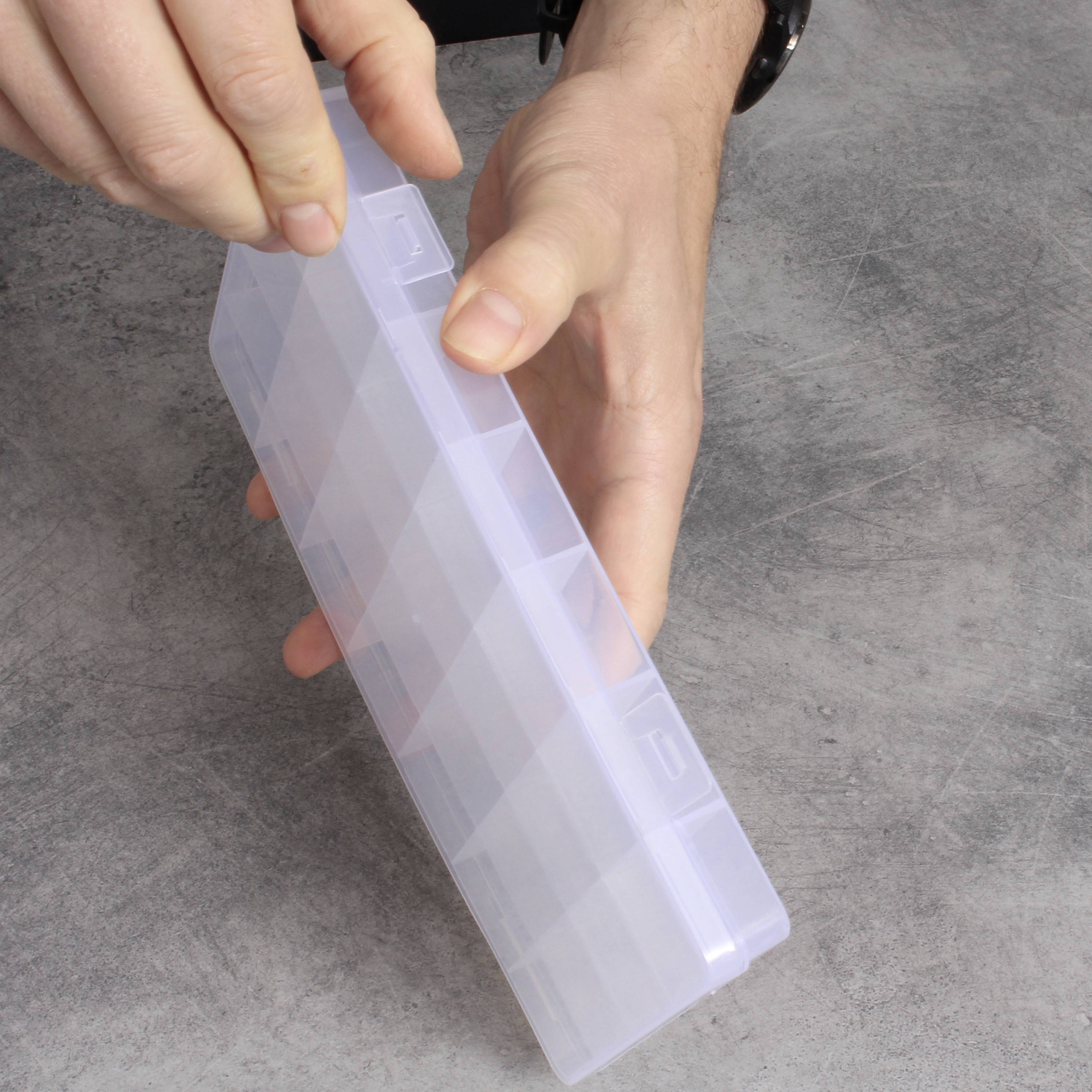 Een persoon houdt een transparante, rechthoekige plastic doos vast op een grijze ondergrond. De deksel van de doos is licht geopend.