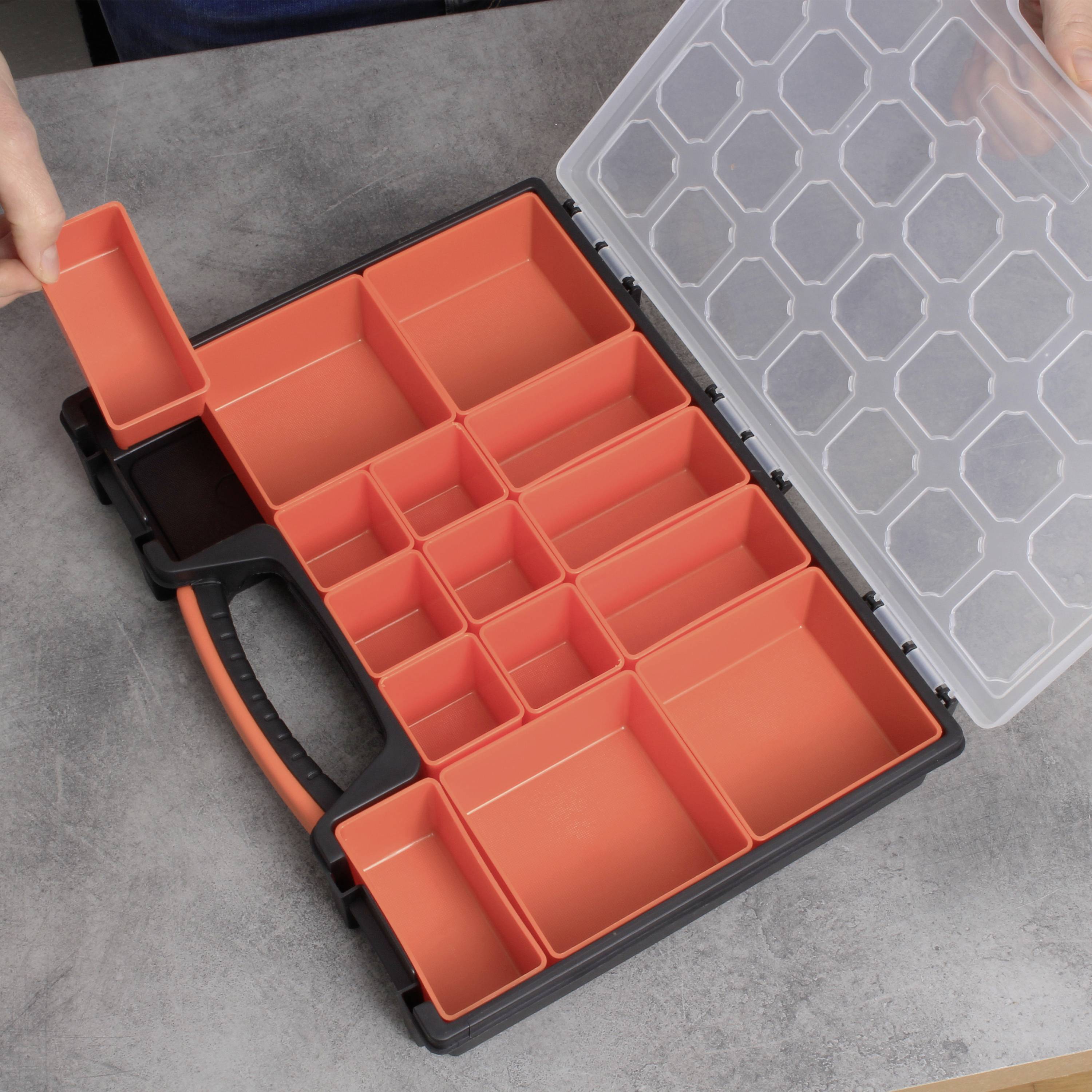 Een geopende opbergdoos met uitneembare, rode vakken op een grijze tafel. Een hand neemt een vak uit.