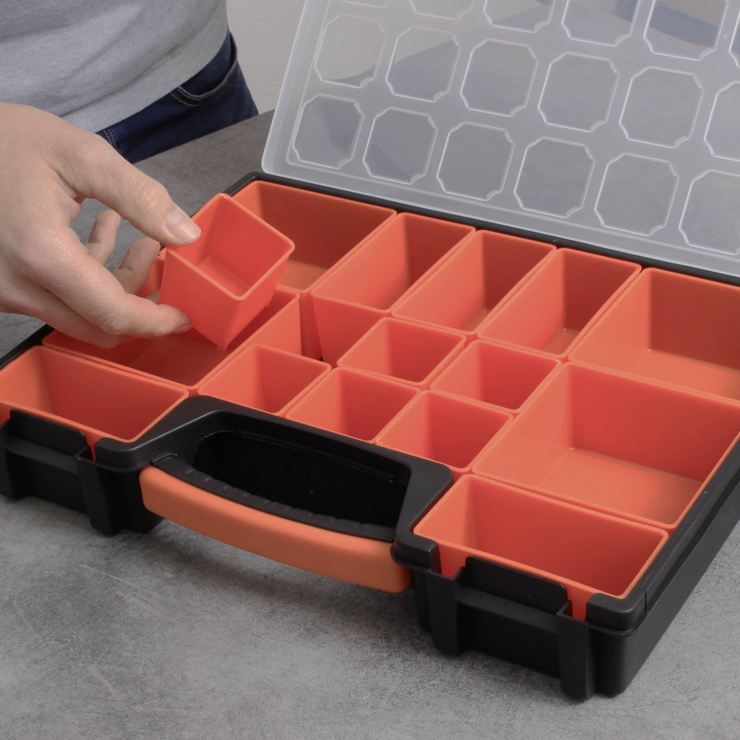 Een geopende gereedschapskoffer met rode, uitneembare vakken op een tafel. Een hand houdt een vak boven de koffer.