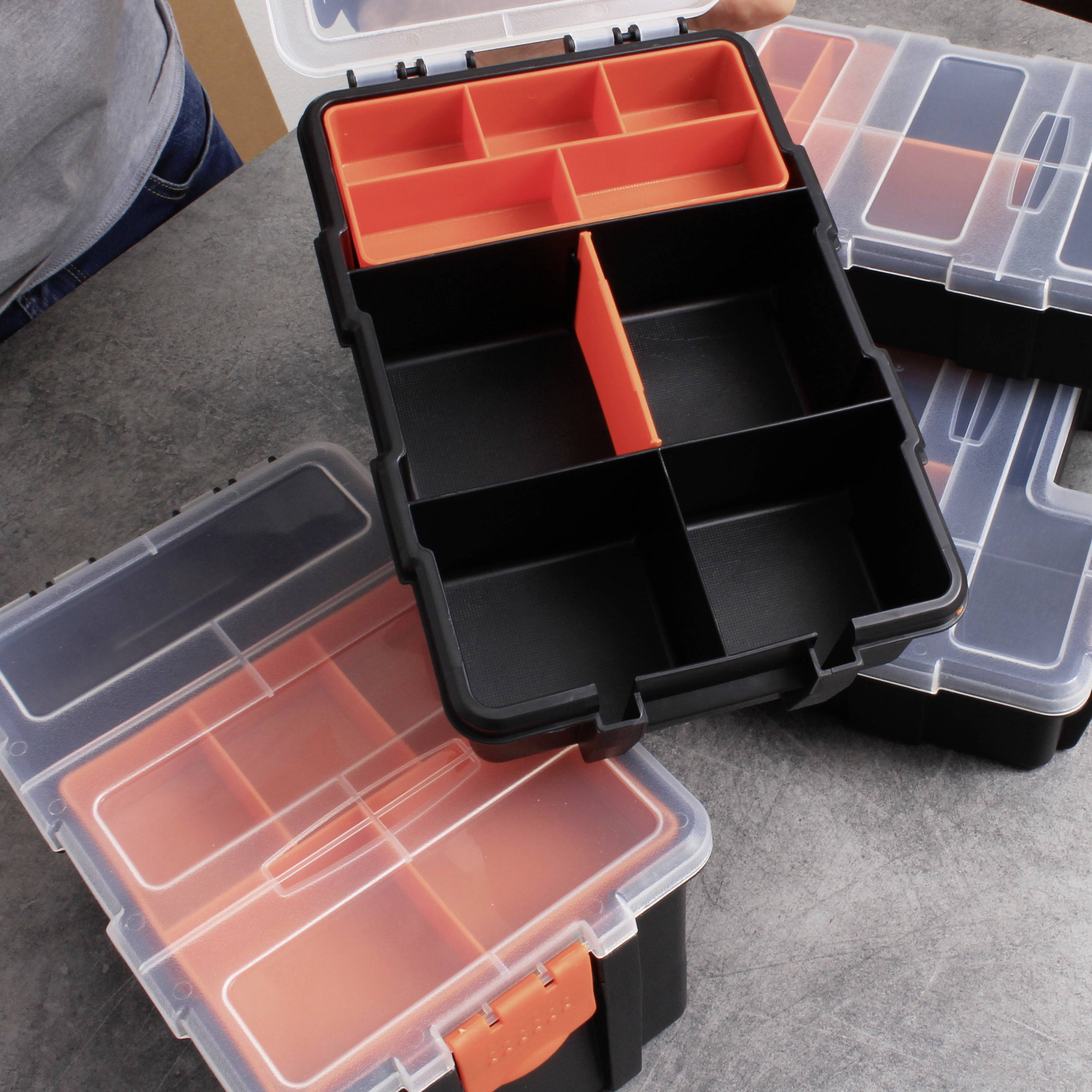 Een open kunststof gereedschapskist met meerdere vakken, ideaal voor georganiseerde opslag van kleine onderdelen op een grijze tafel.
