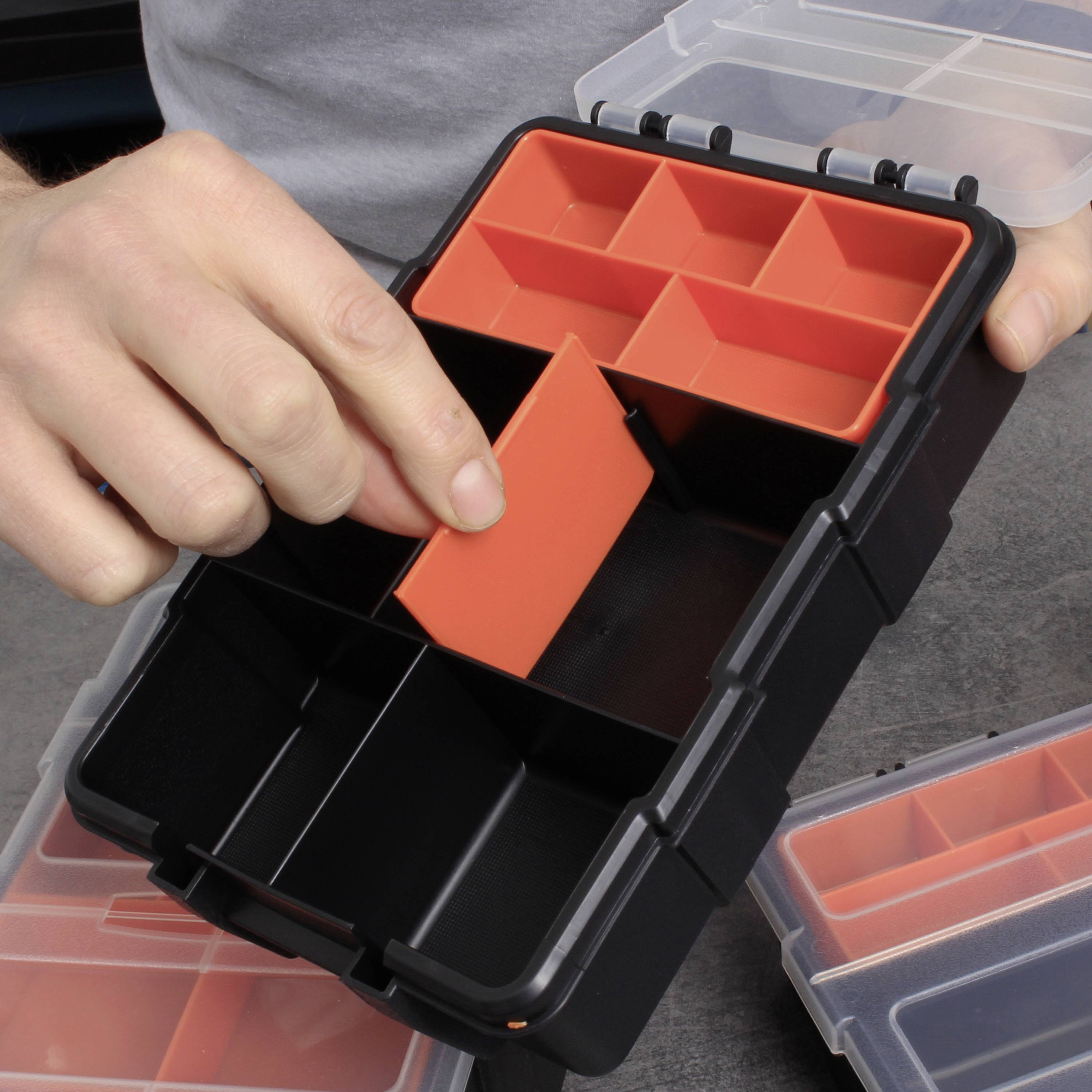 Een open, zwarte opbergdoos met uitneembare, rode vakken wordt door een hand aangepast.