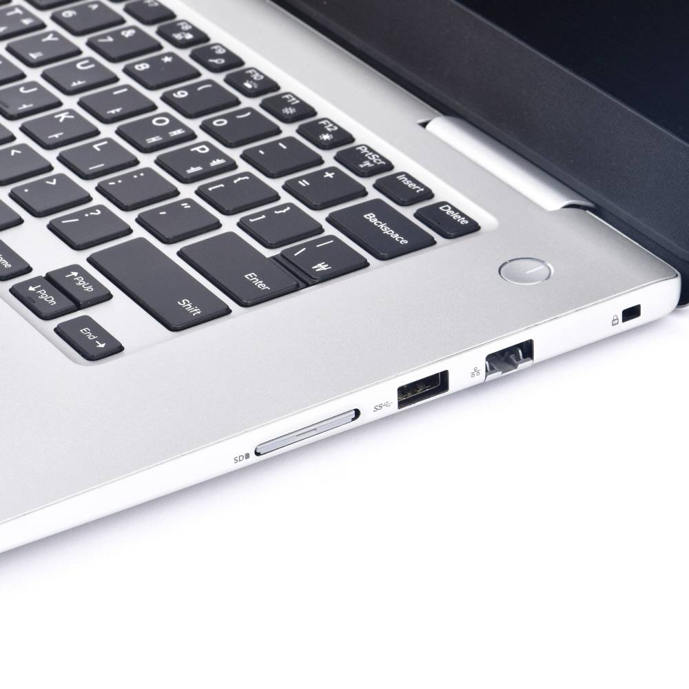 Een zilveren laptop met zwart toetsenbord, gezien van opzij. USB- en netaansluitingen zijn zichtbaar.