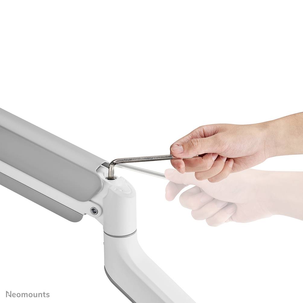 Een hand stelt met een inbussleutel de vering van een monitorarm af.
