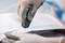 'Handen met handschoenen gebruiken een snijgereedschap om wit papier te knippen.'