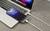 Een smartphone wordt opgeladen via een kabel die is aangesloten op een laptop. Op het scherm van de smartphone wordt de tijd '10:56' weergegeven.