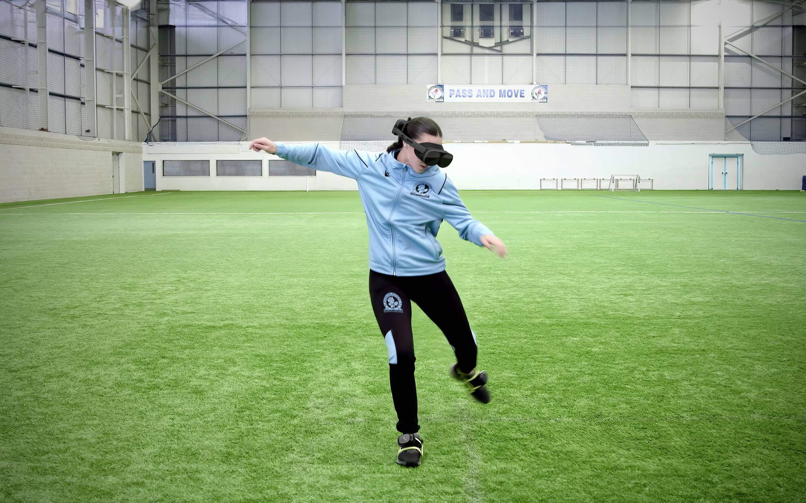 Een persoon op een groen sportveld draagt een blinddoek en sportkleding. Ze strekt de armen uit en beweegt zich voorzichtig.