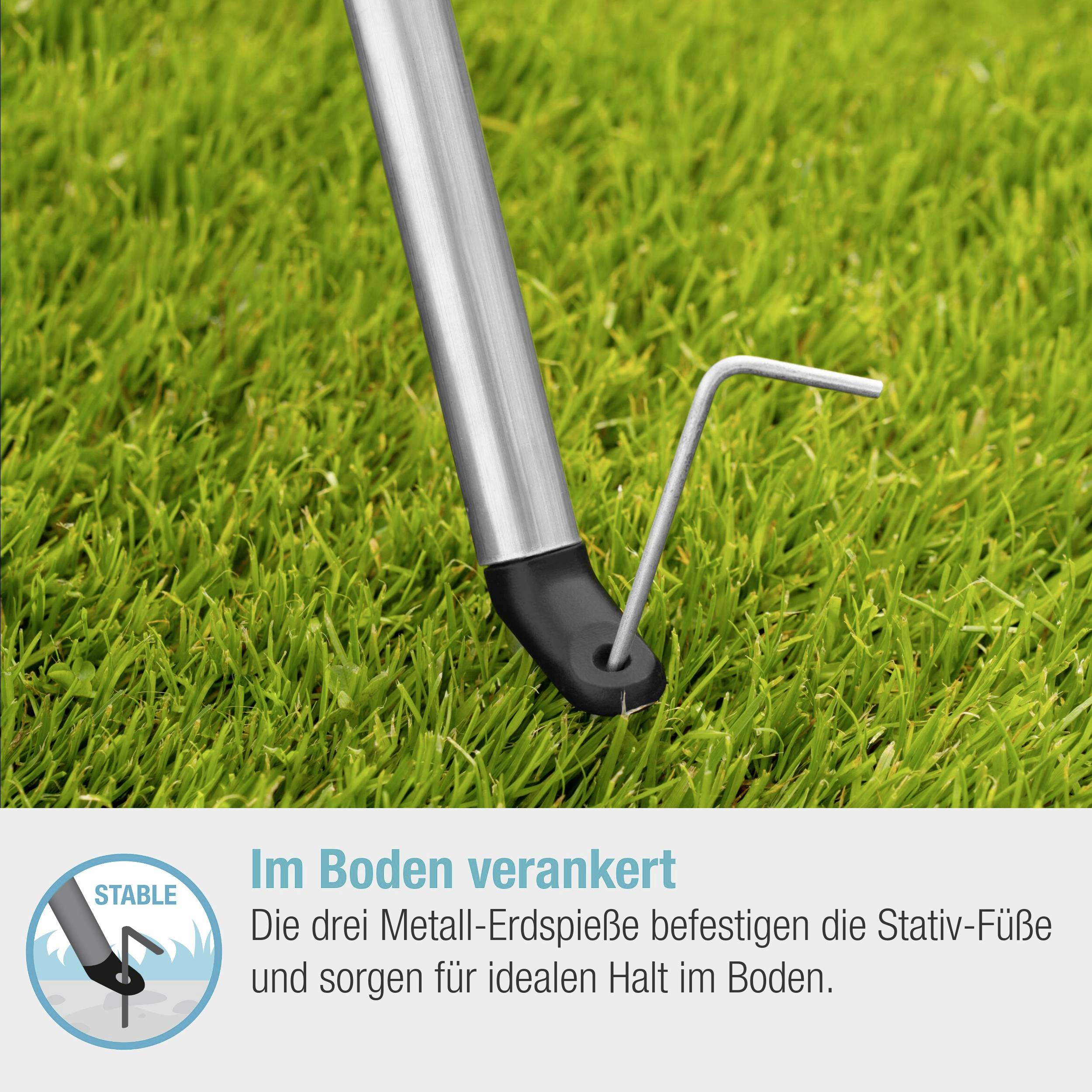 'Een metalen grondpen verankert de statief-voeten in de grond en zorgt voor stabiliteit op een grasveld.'
