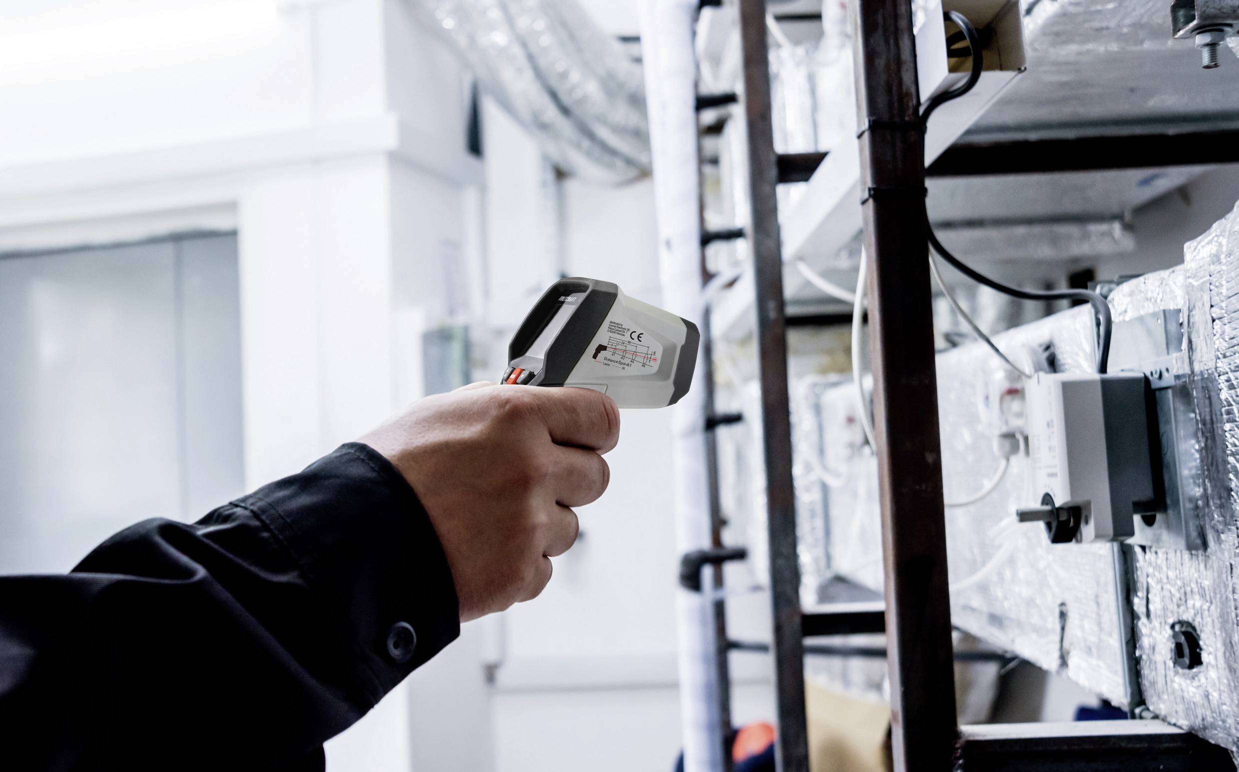 Een persoon meet de temperatuur van een verwarmingsinstallatie met een infrarood-thermometer.