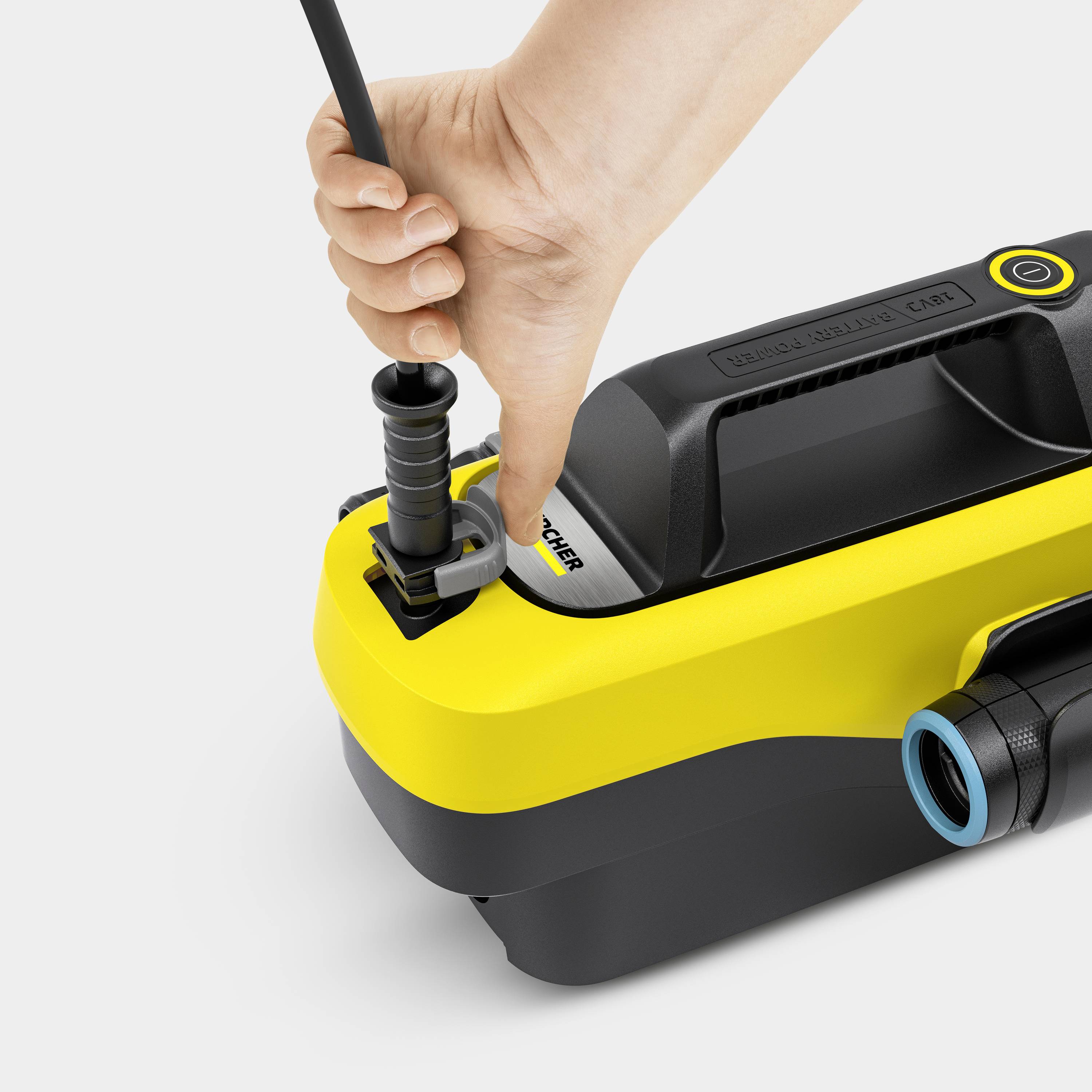 Hand van een mens die een kabel aansluit op een geel-zwart Kärcher-apparaat.