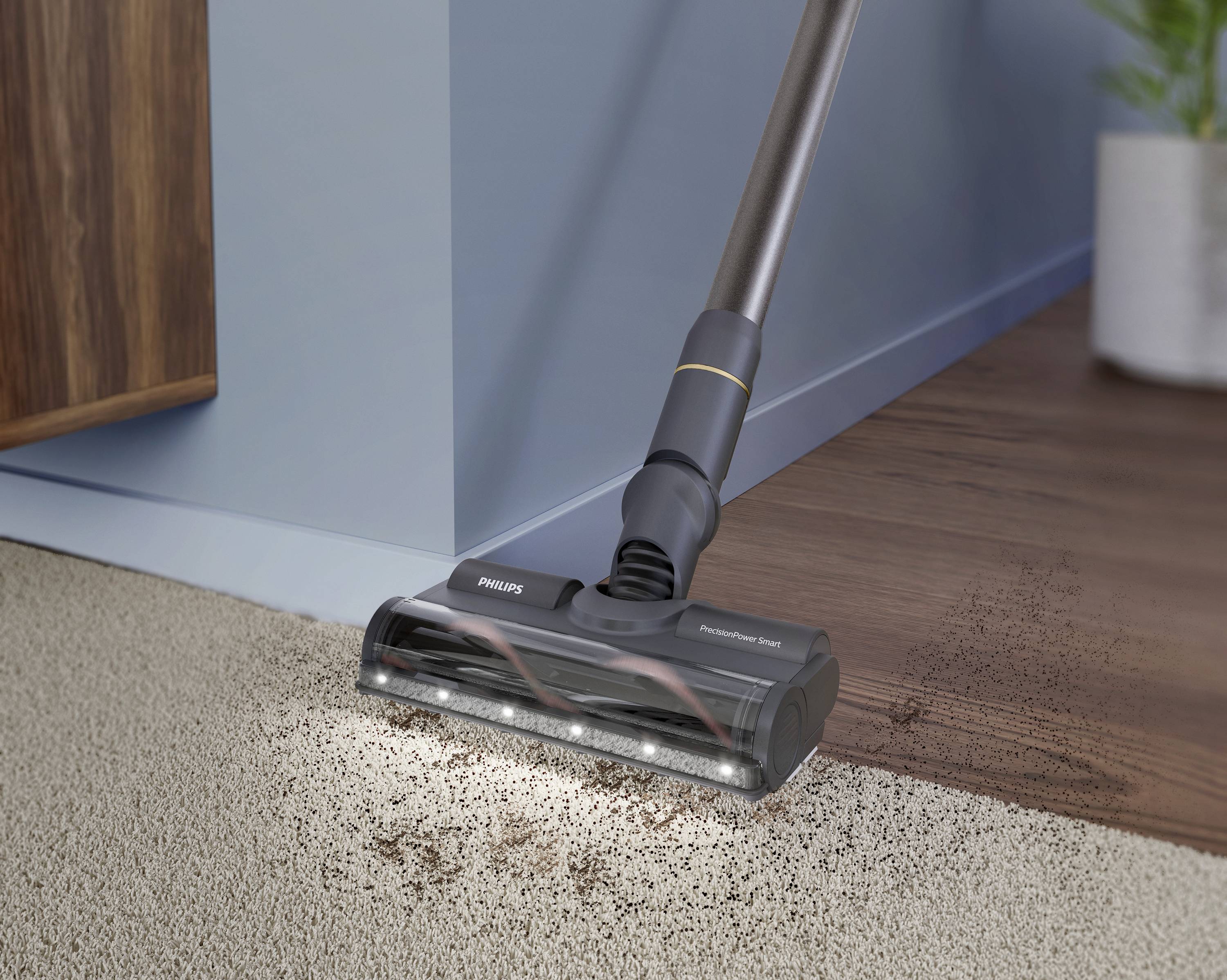 Een stofzuigerkop zuigt vuil van een tapijt bij de overgang naar een houten vloer.